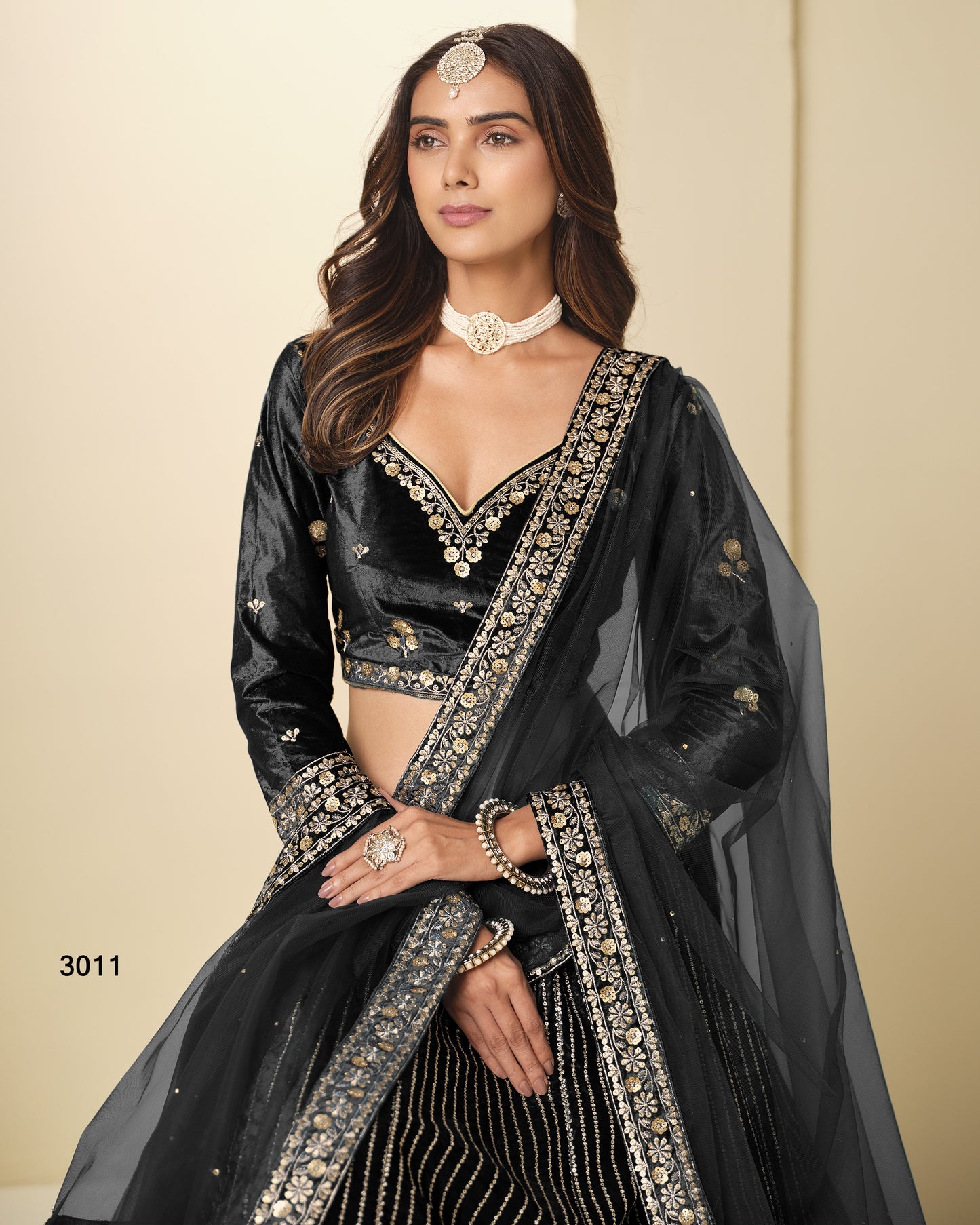Woman wearing a black saree with gold embroidery on a beige background