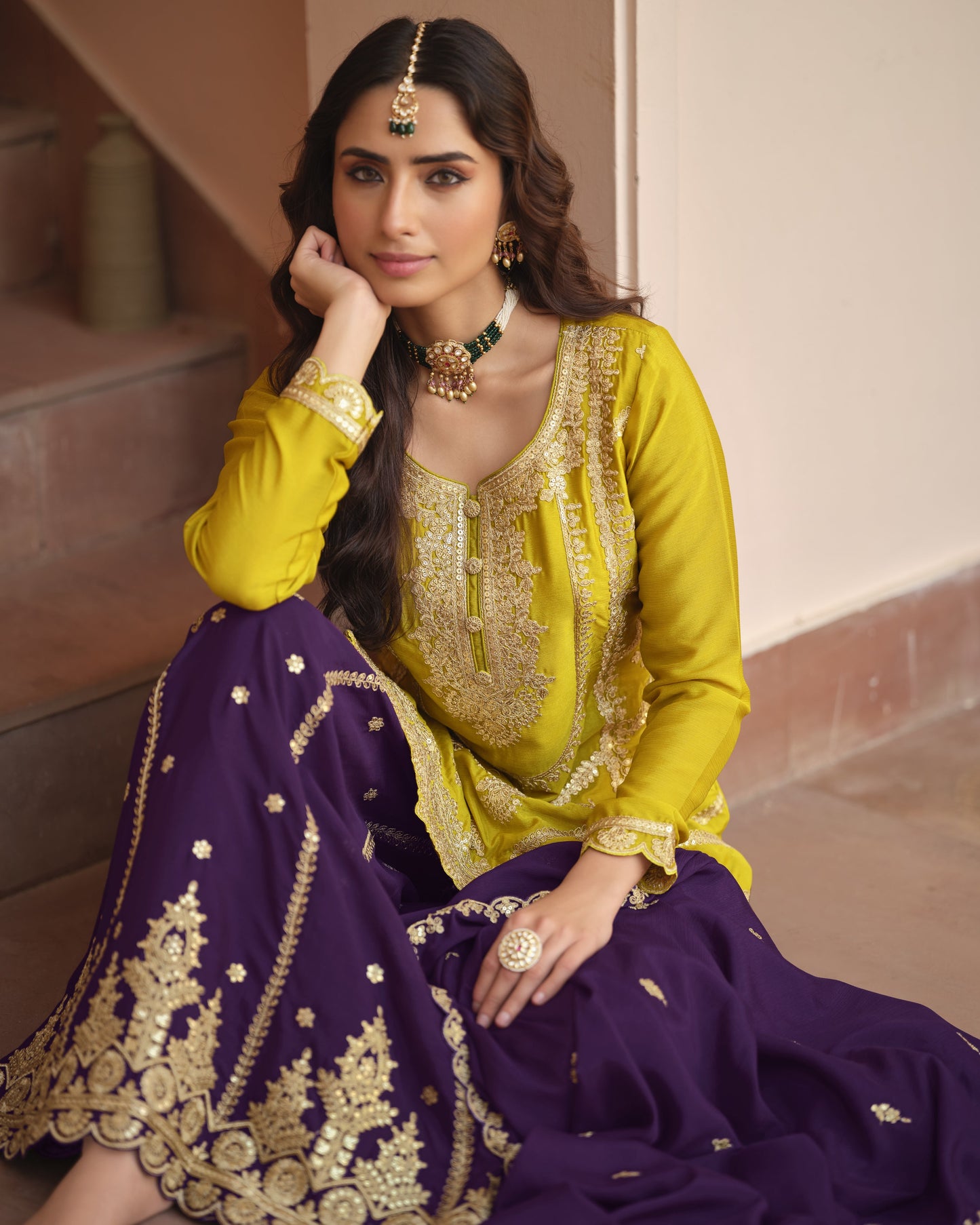 Woman wearing a yellow and purple traditional outfit with gold embroidery.