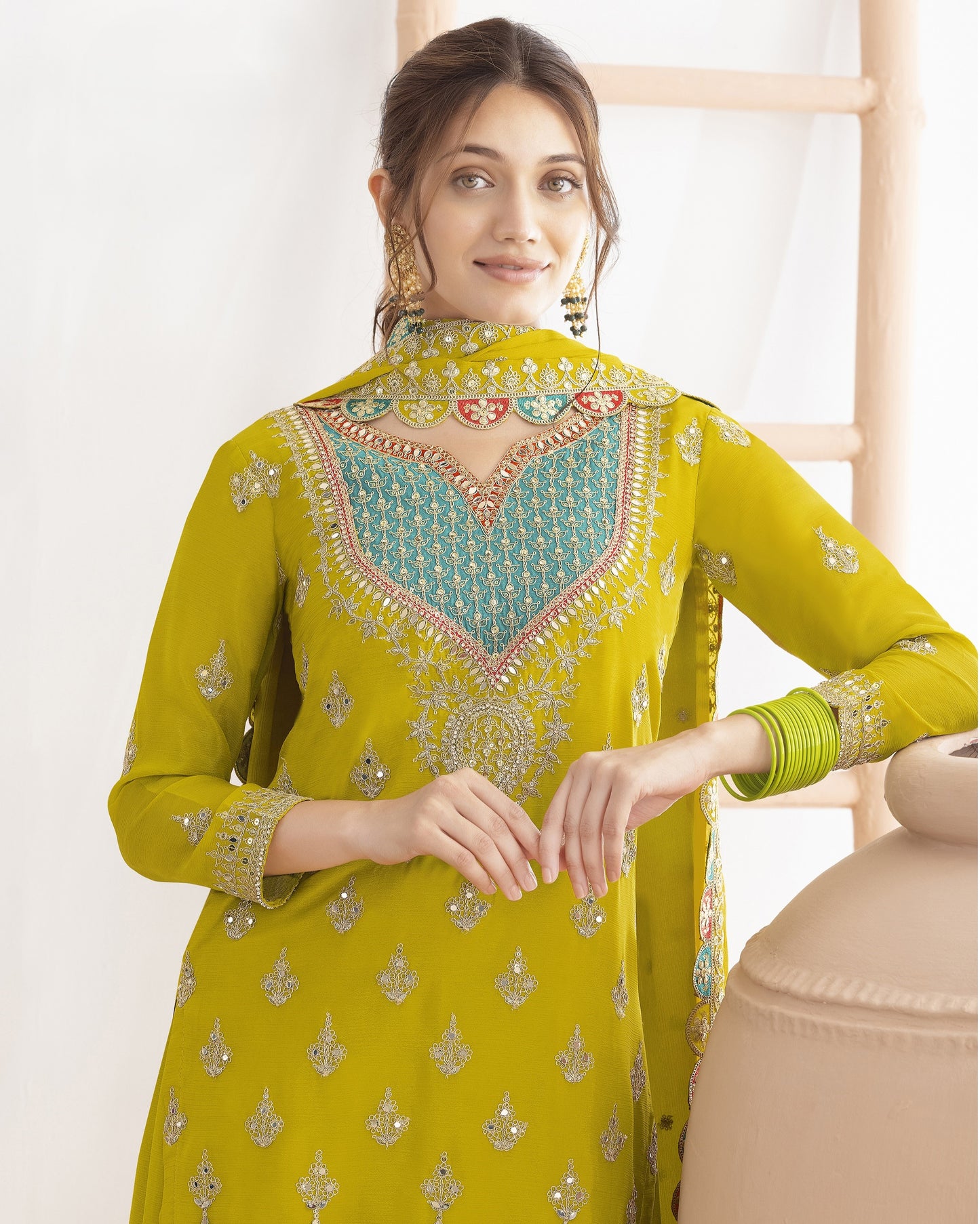 Woman wearing a yellow embroidered traditional outfit with a white background