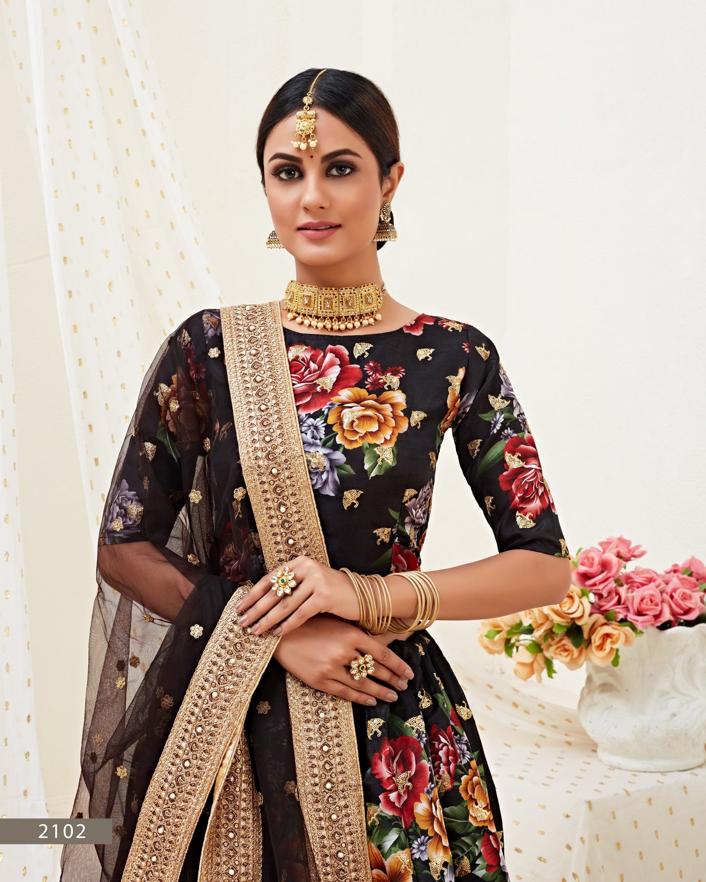 Woman wearing a floral saree with a gold border against a white background