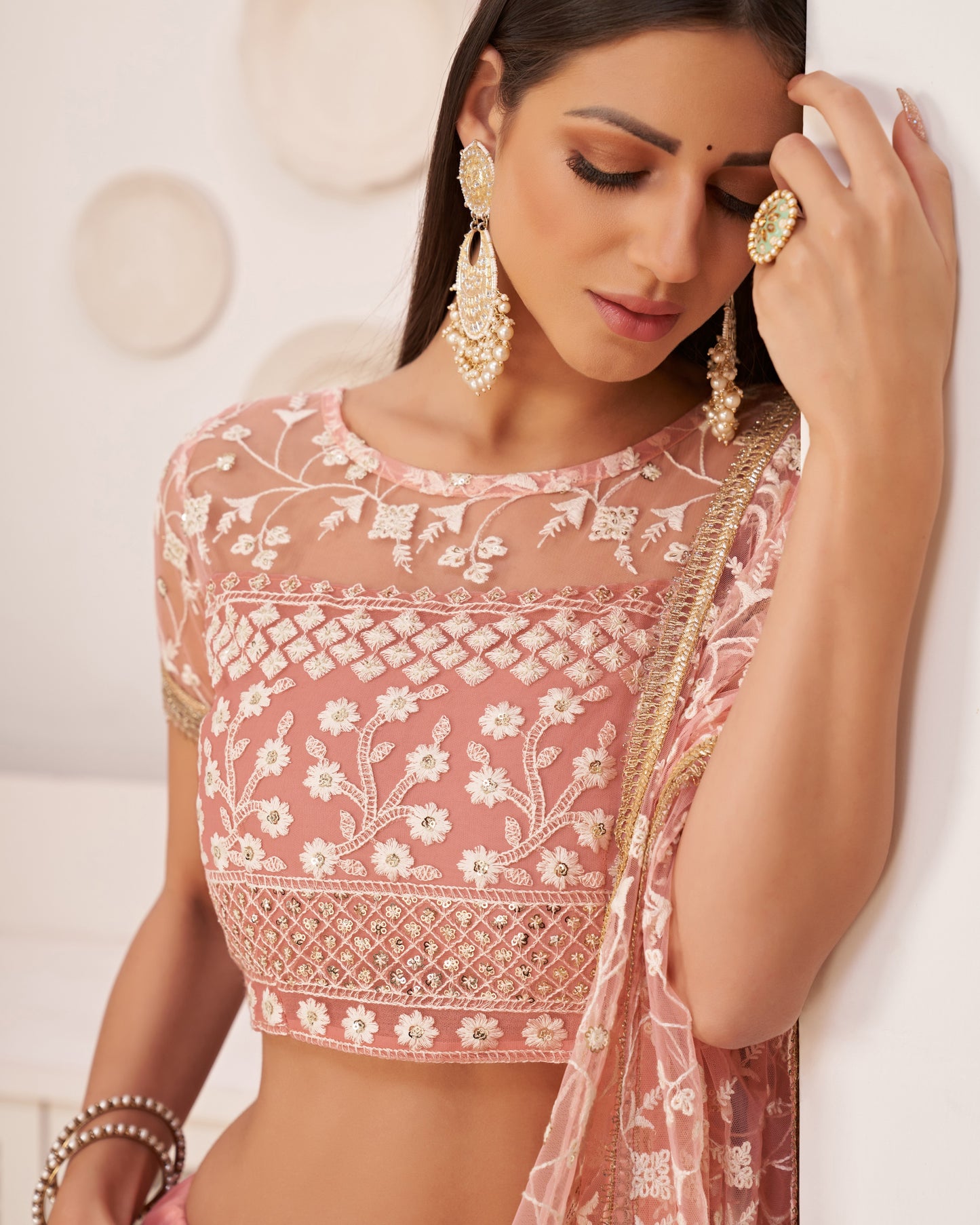 Woman wearing a pink embroidered blouse with a white background