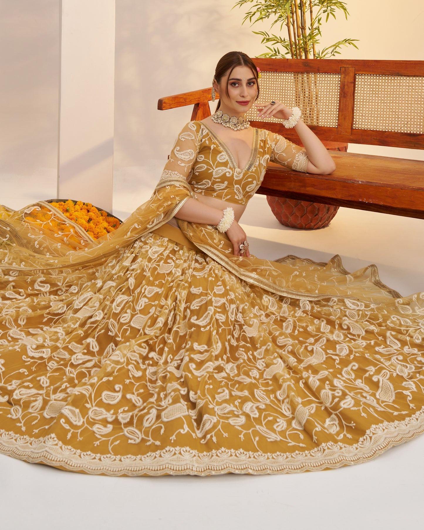 Woman in a yellow embroidered traditional outfit sitting on a wooden bench.