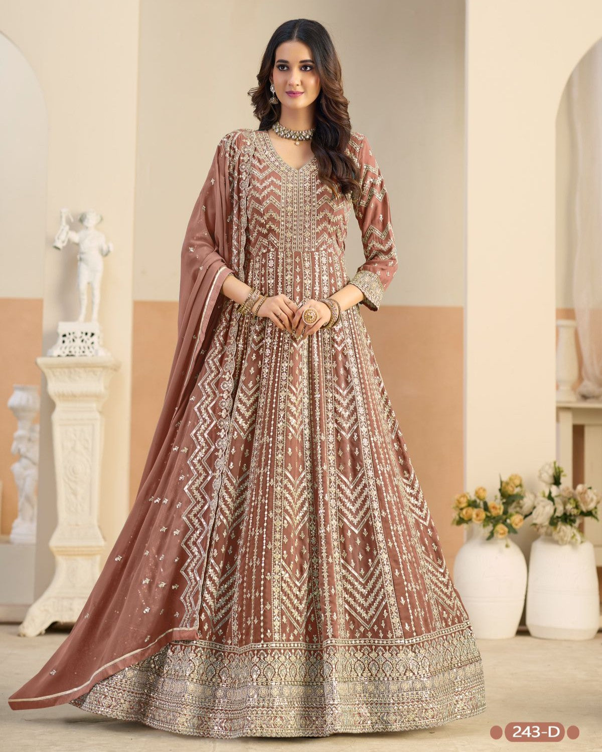 Woman wearing a traditional outfit with a patterned dress and dupatta in an indoor setting.