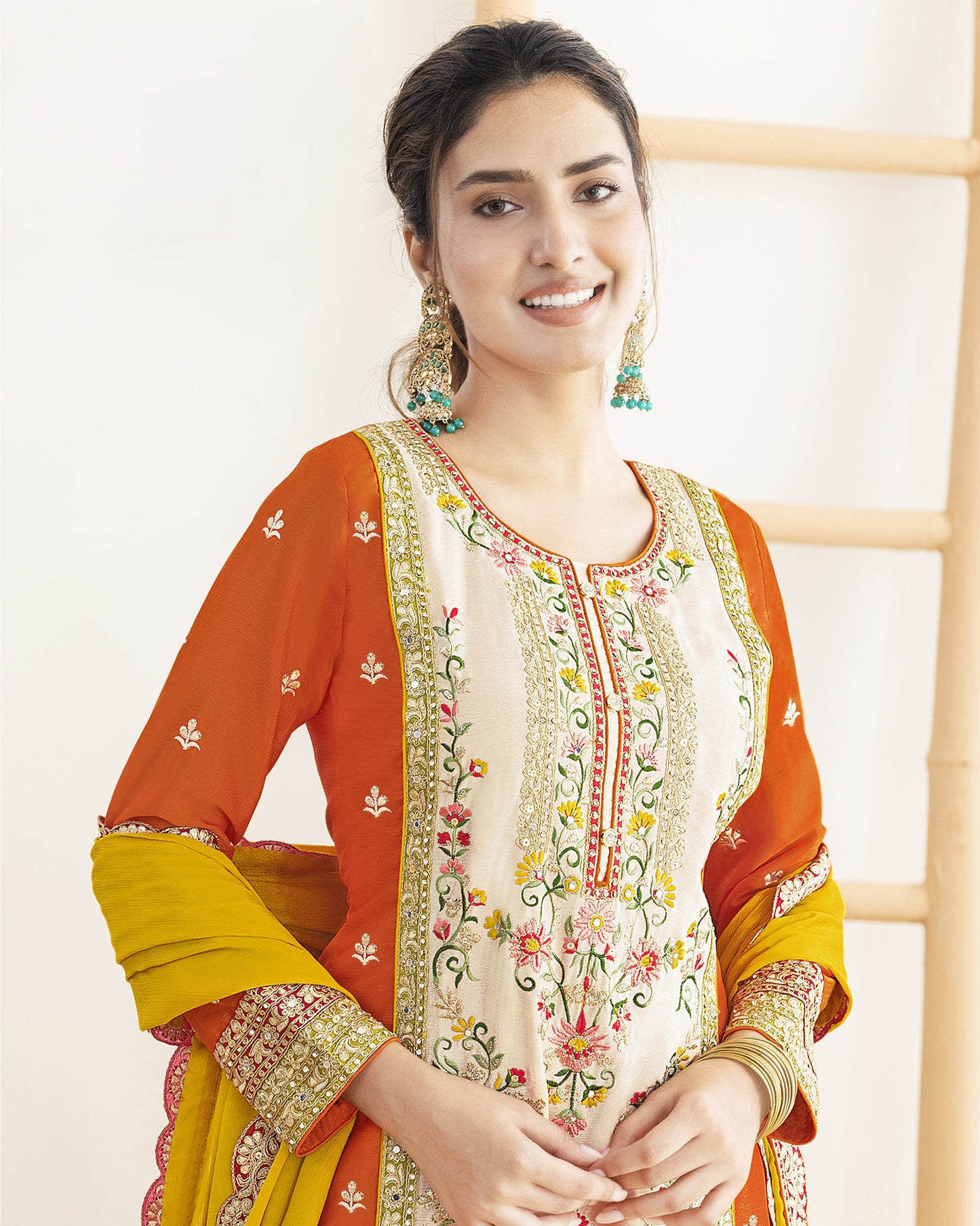 Woman wearing a traditional outfit with orange, yellow, and white colors on a light background