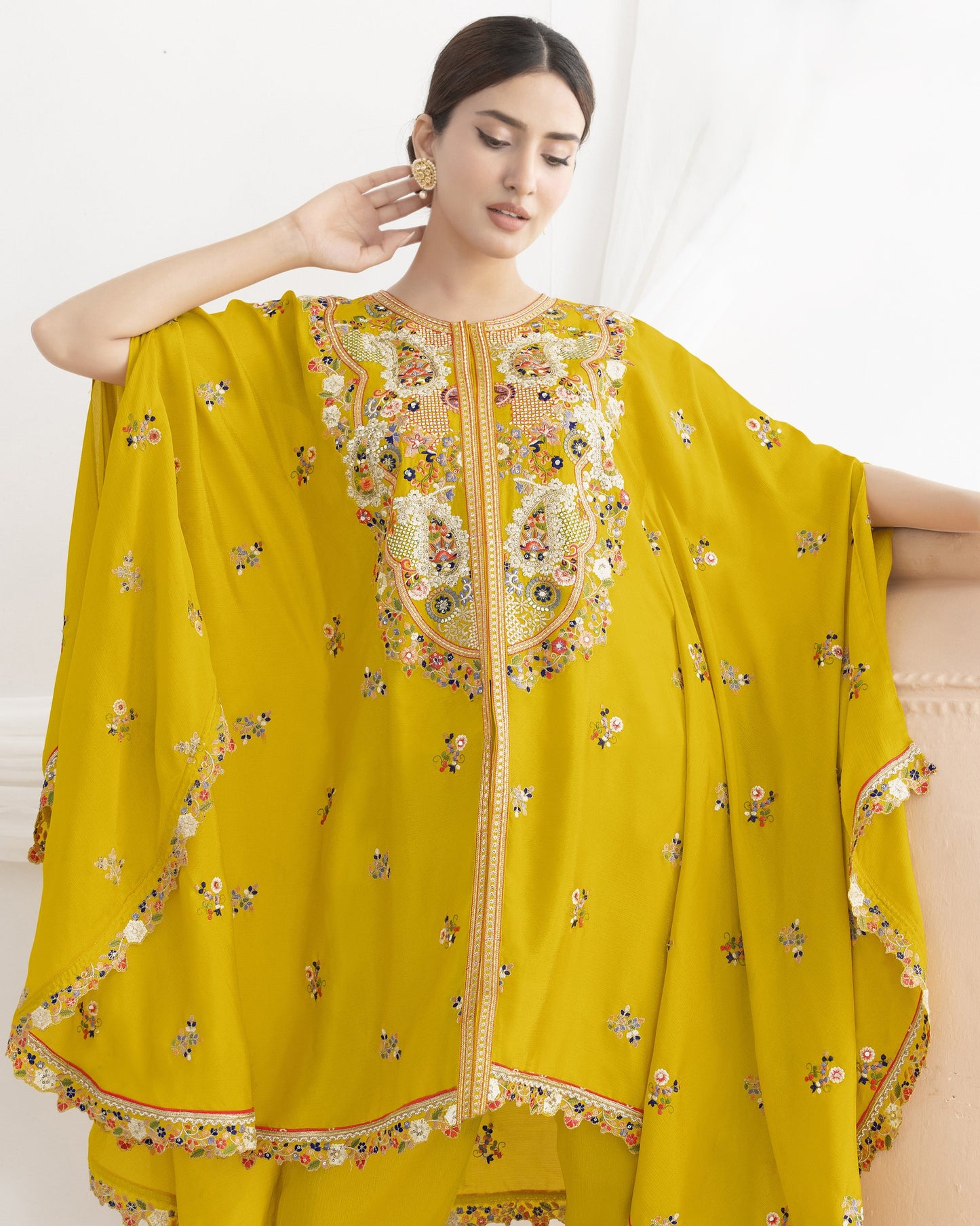 Woman wearing a yellow embroidered traditional outfit with a white background