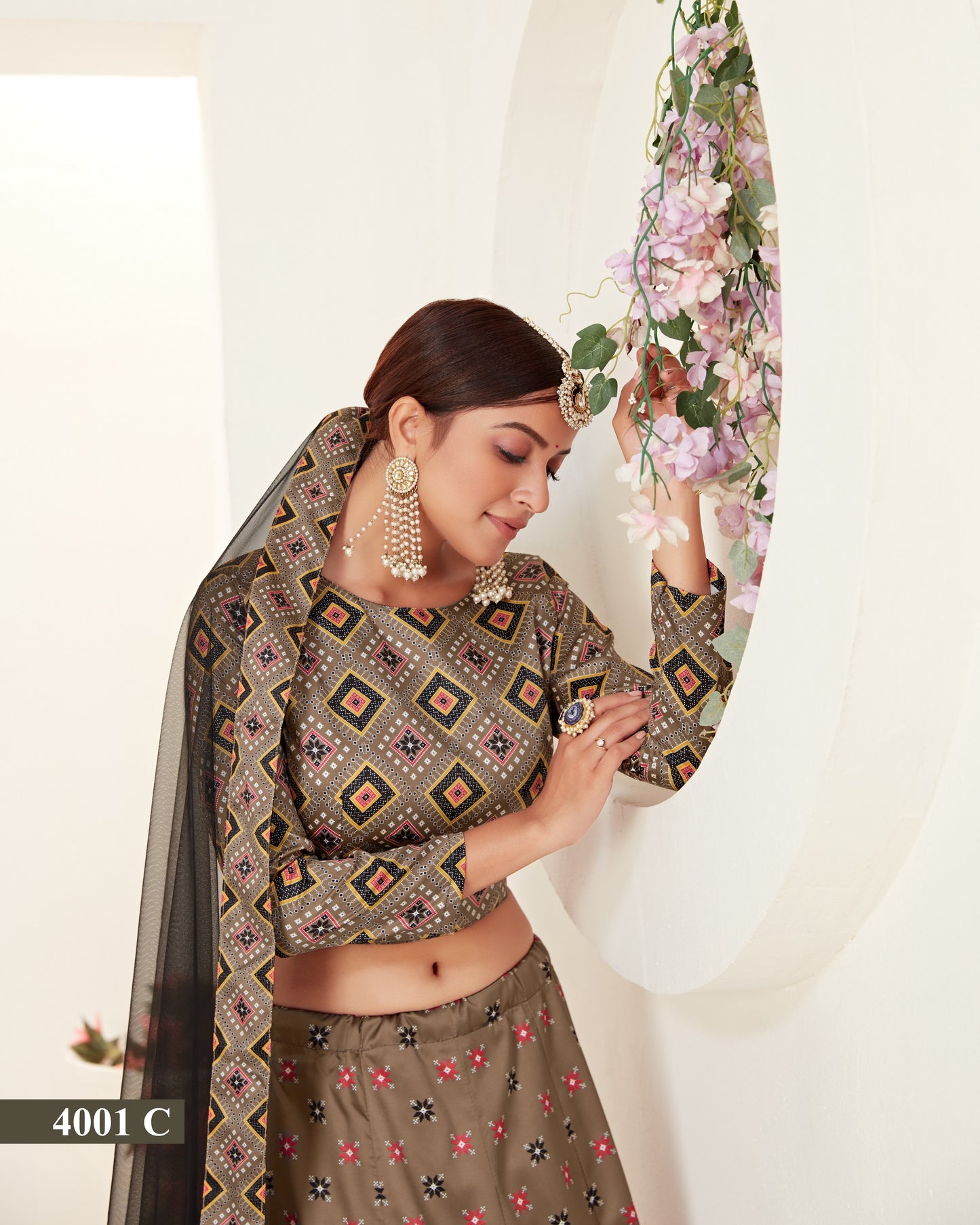 Woman in traditional outfit with floral decorations and jewelry against a white background