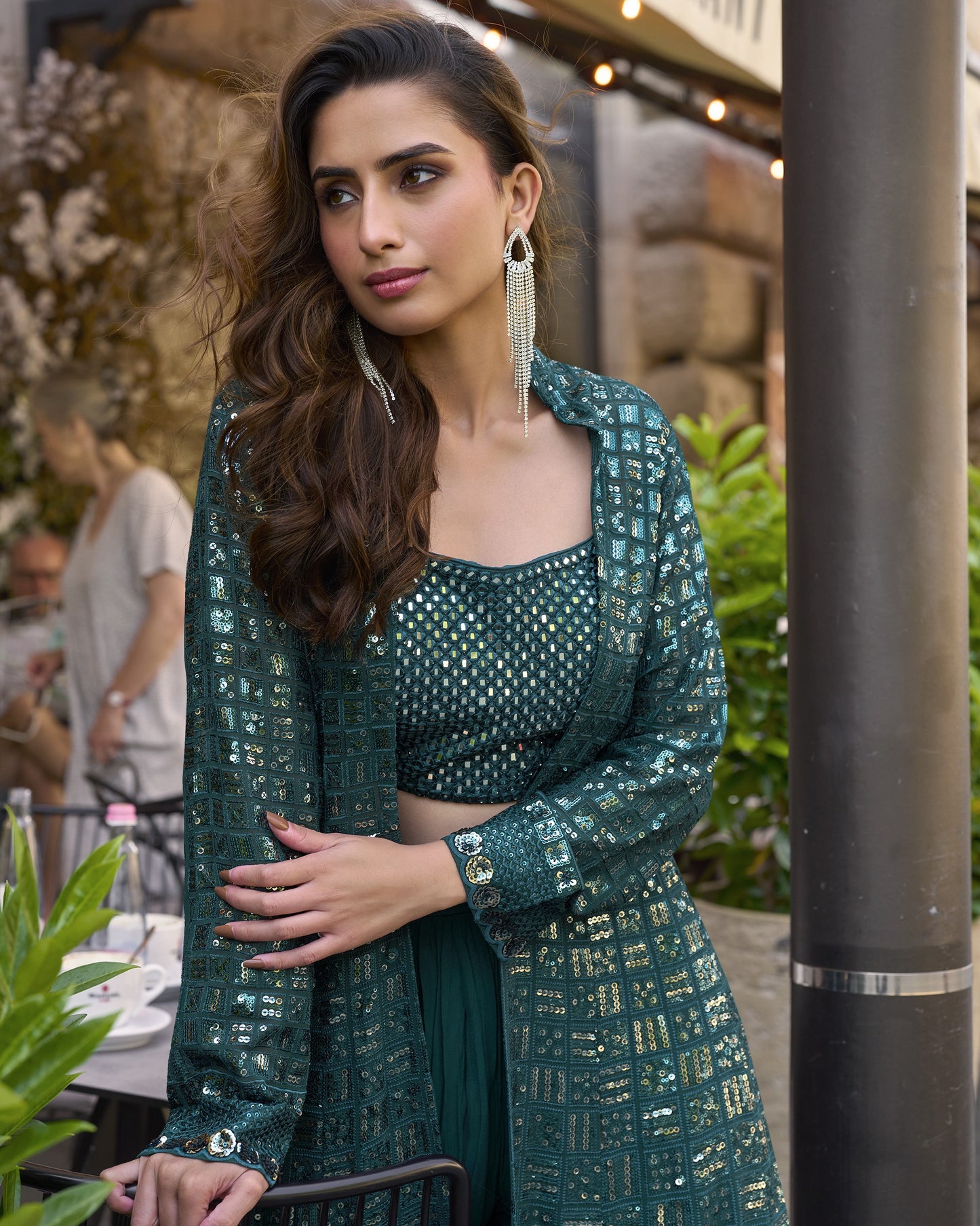 Woman in a green traditional outfit standing outdoors with blurred background
