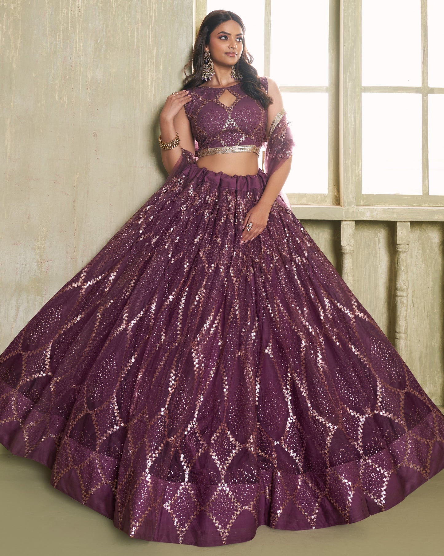 Woman wearing a purple sequined outfit in front of a window.
