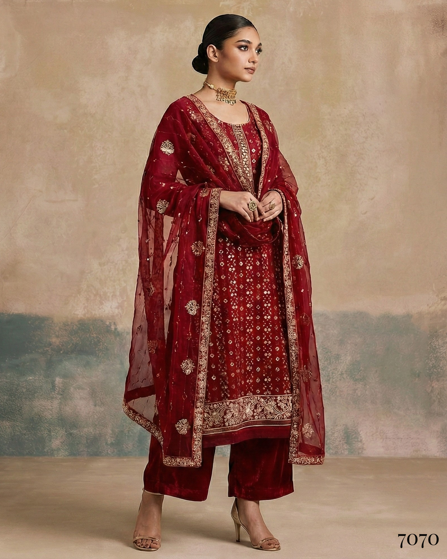 Woman wearing a traditional red outfit with gold embroidery against a textured beige background