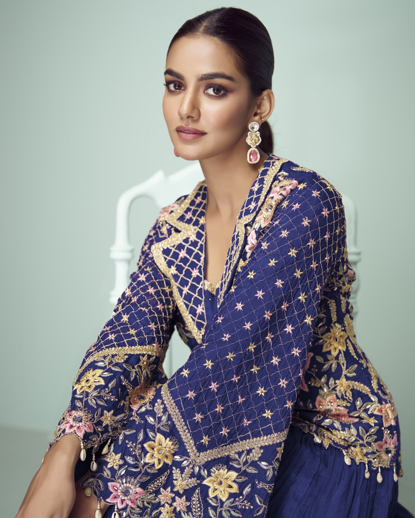 Woman wearing a blue embroidered traditional outfit with a white background