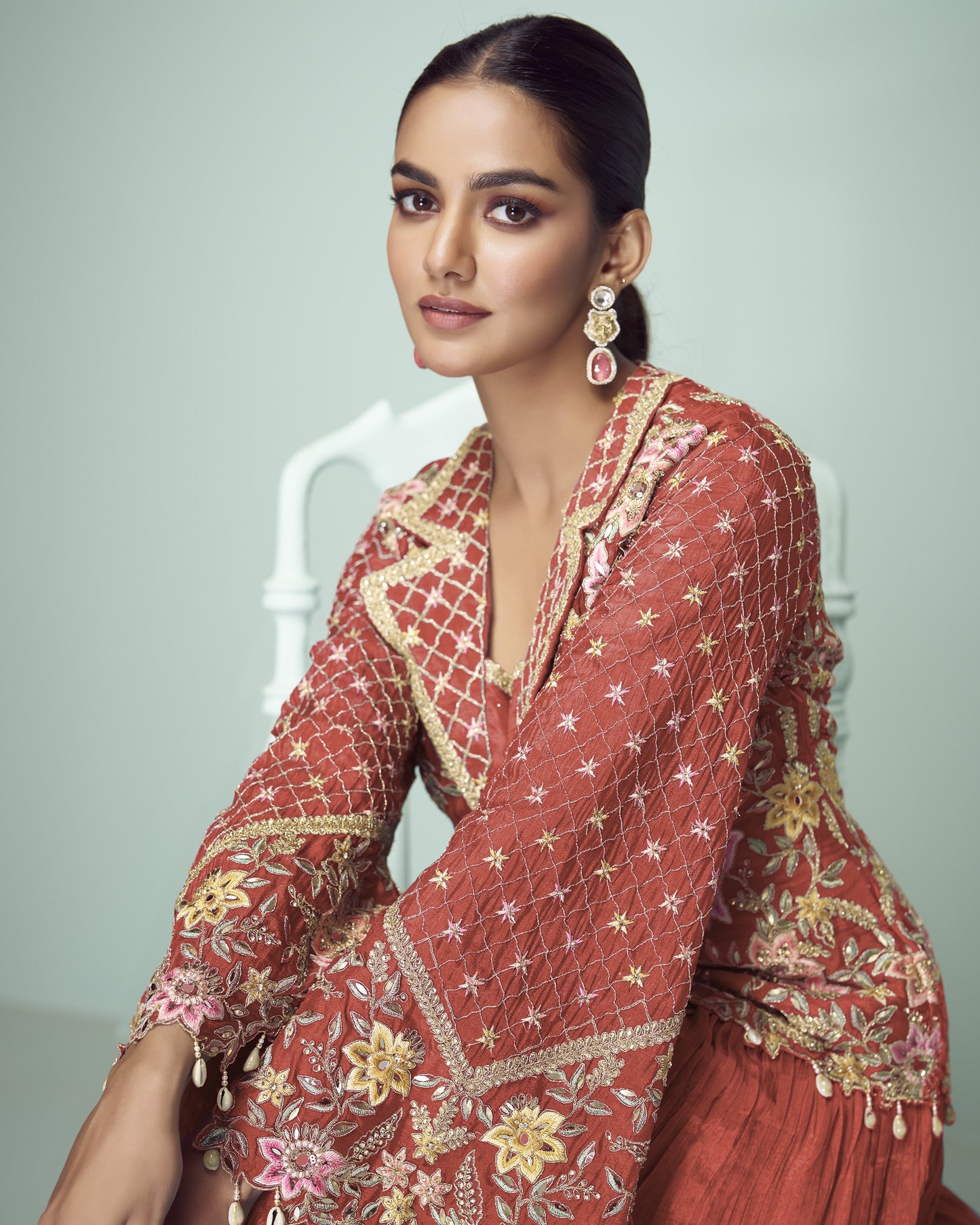 Woman wearing a red embroidered traditional outfit with a neutral background