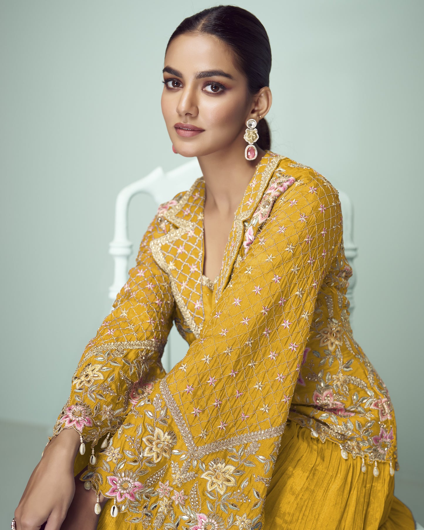Woman wearing a yellow embroidered traditional outfit with a neutral background