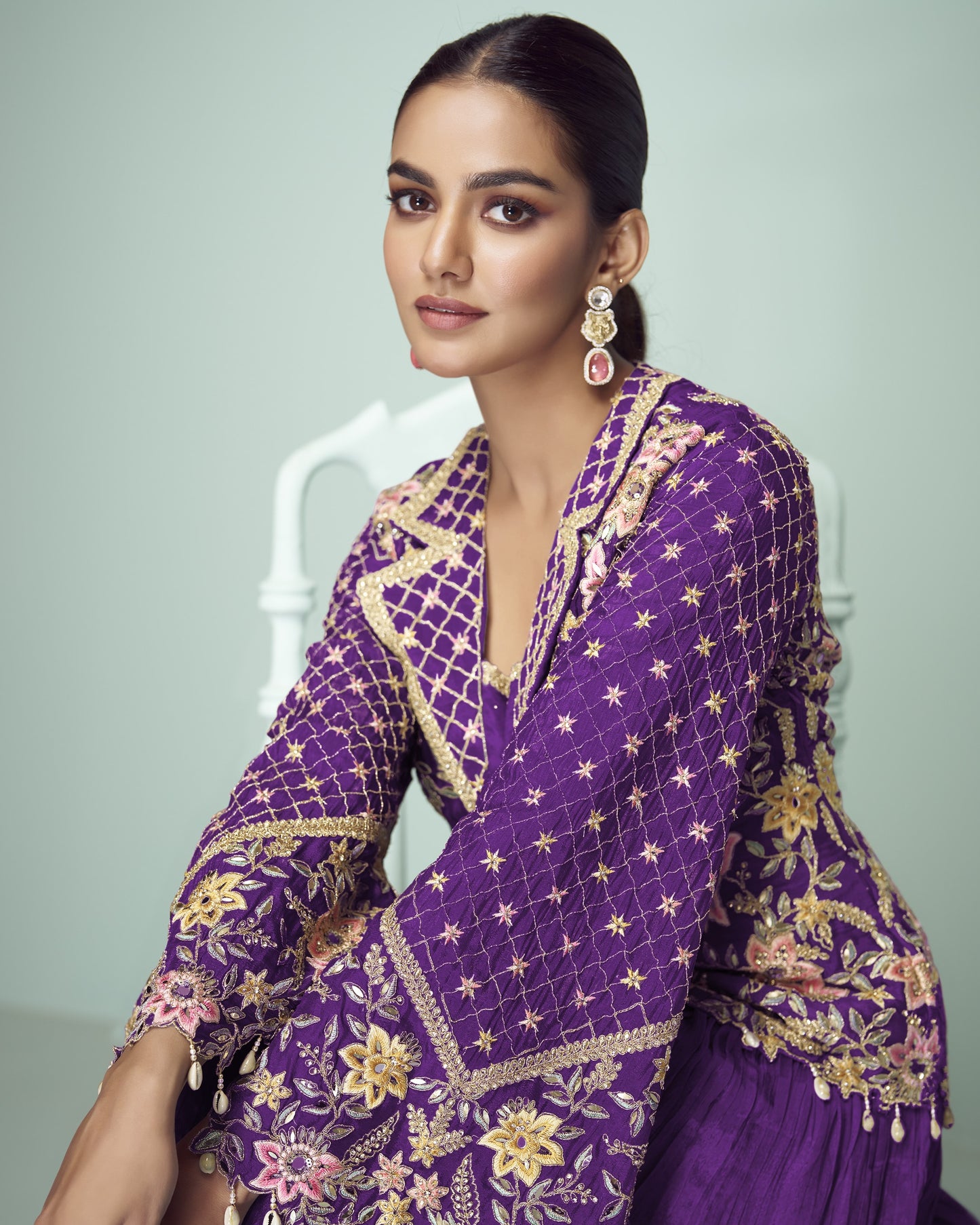 Woman wearing a purple embroidered traditional outfit with a neutral background