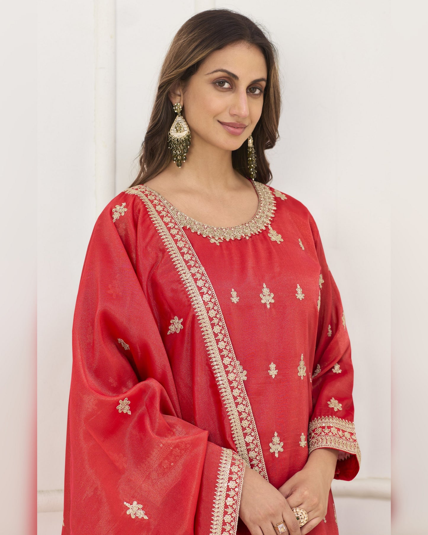 Woman wearing a red traditional outfit with gold embroidery against a white background