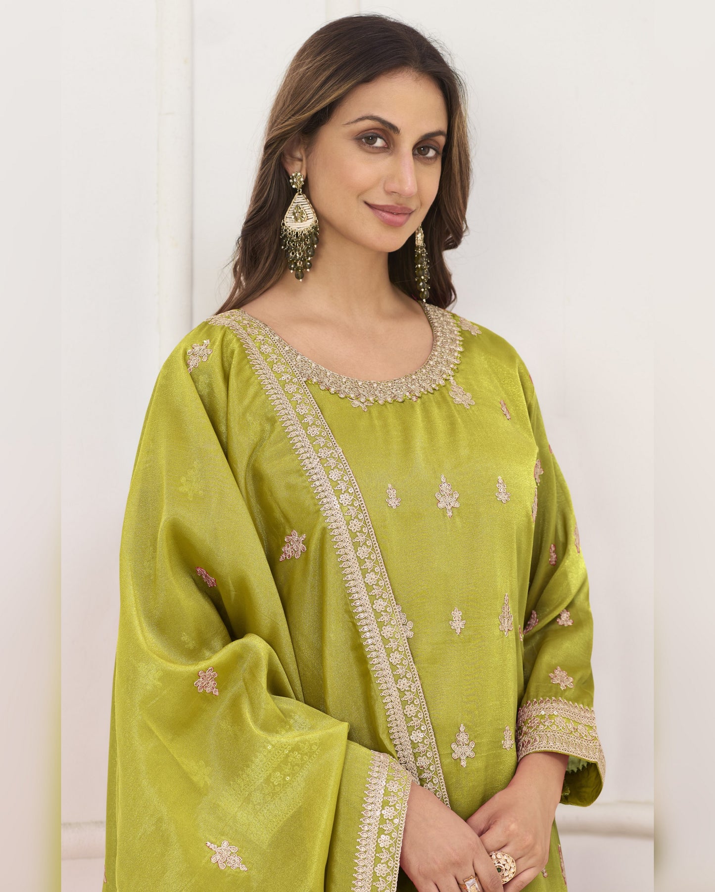 Woman wearing a green embroidered traditional outfit against a white background