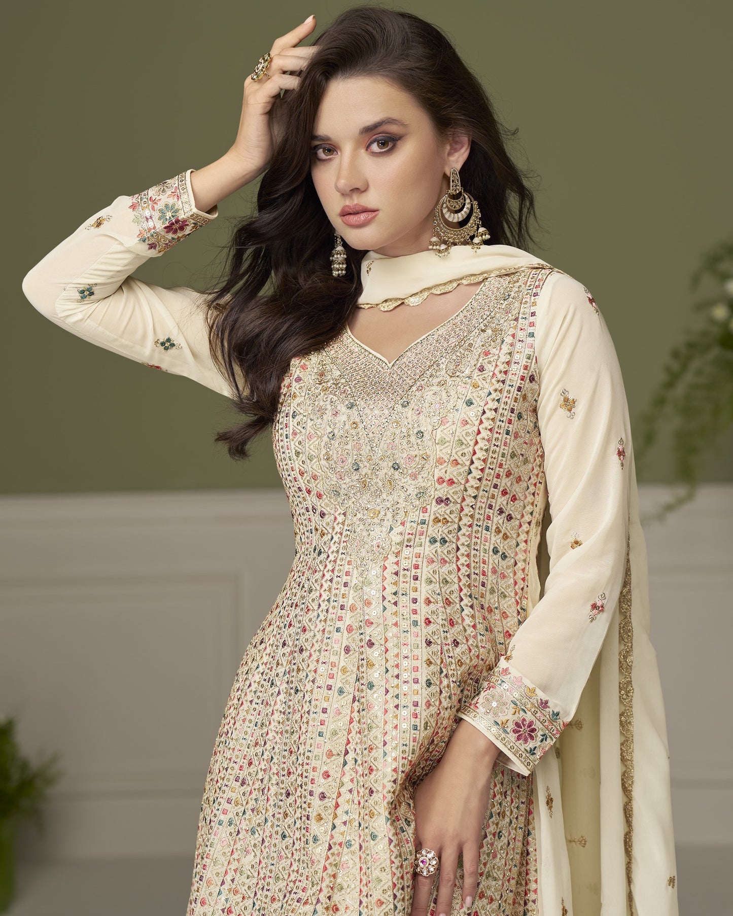 Woman wearing a traditional embroidered outfit with a plain background
