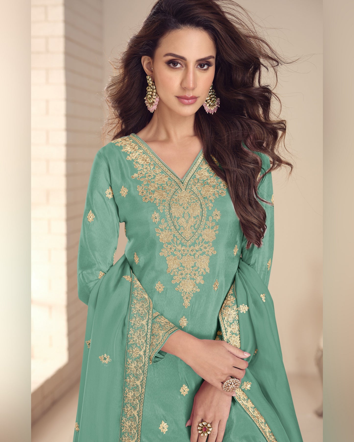 Woman wearing a green embroidered traditional outfit with gold details.