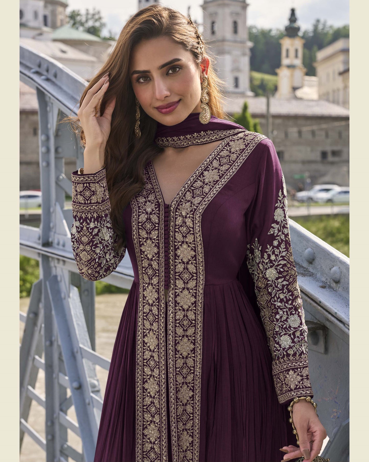 Woman in a purple dress with intricate patterns standing outdoors.