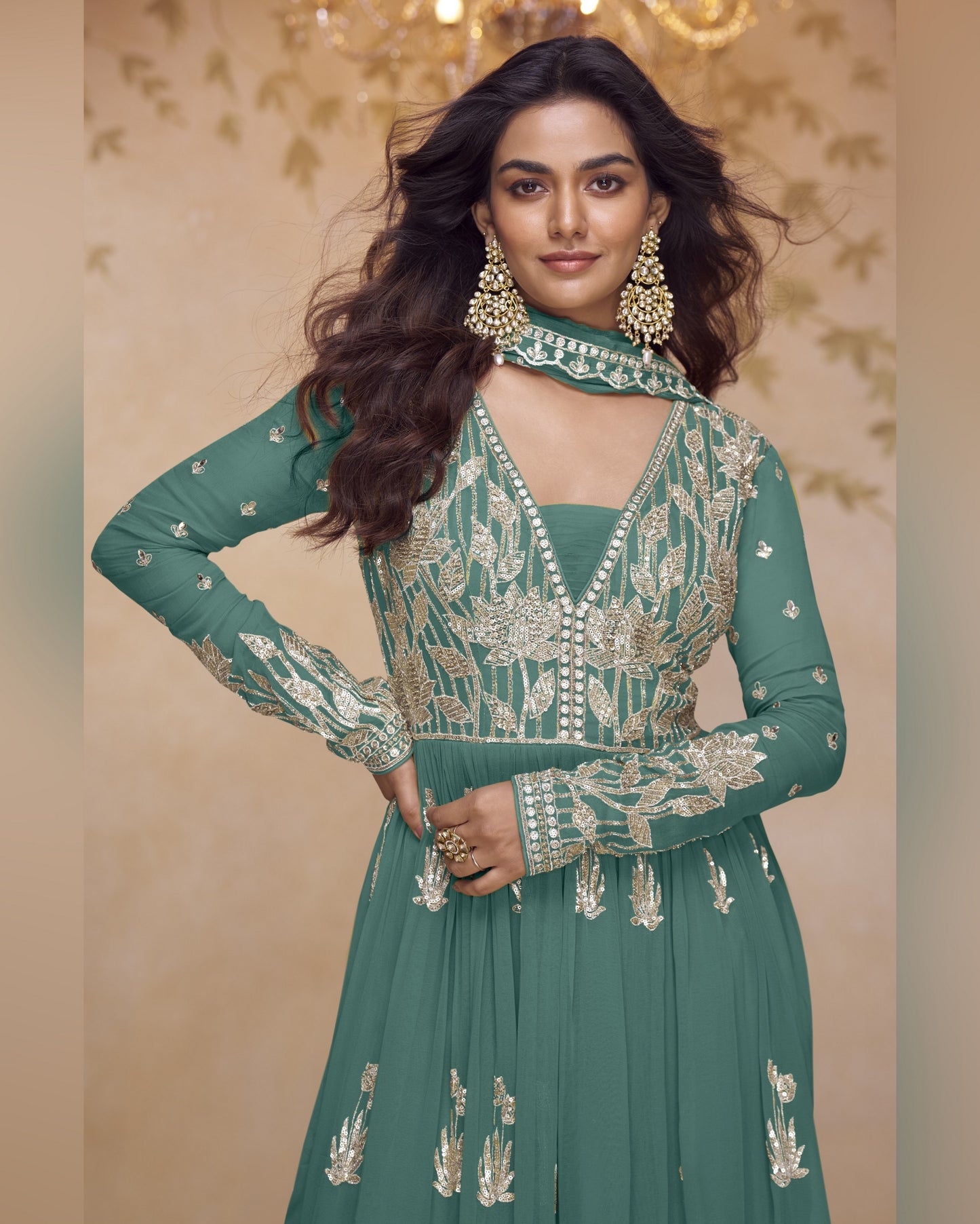 Woman wearing a green embroidered outfit with gold details against a beige background