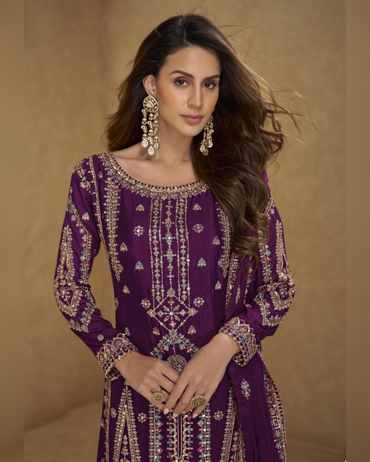 Woman wearing a purple embroidered outfit with gold details against a beige background