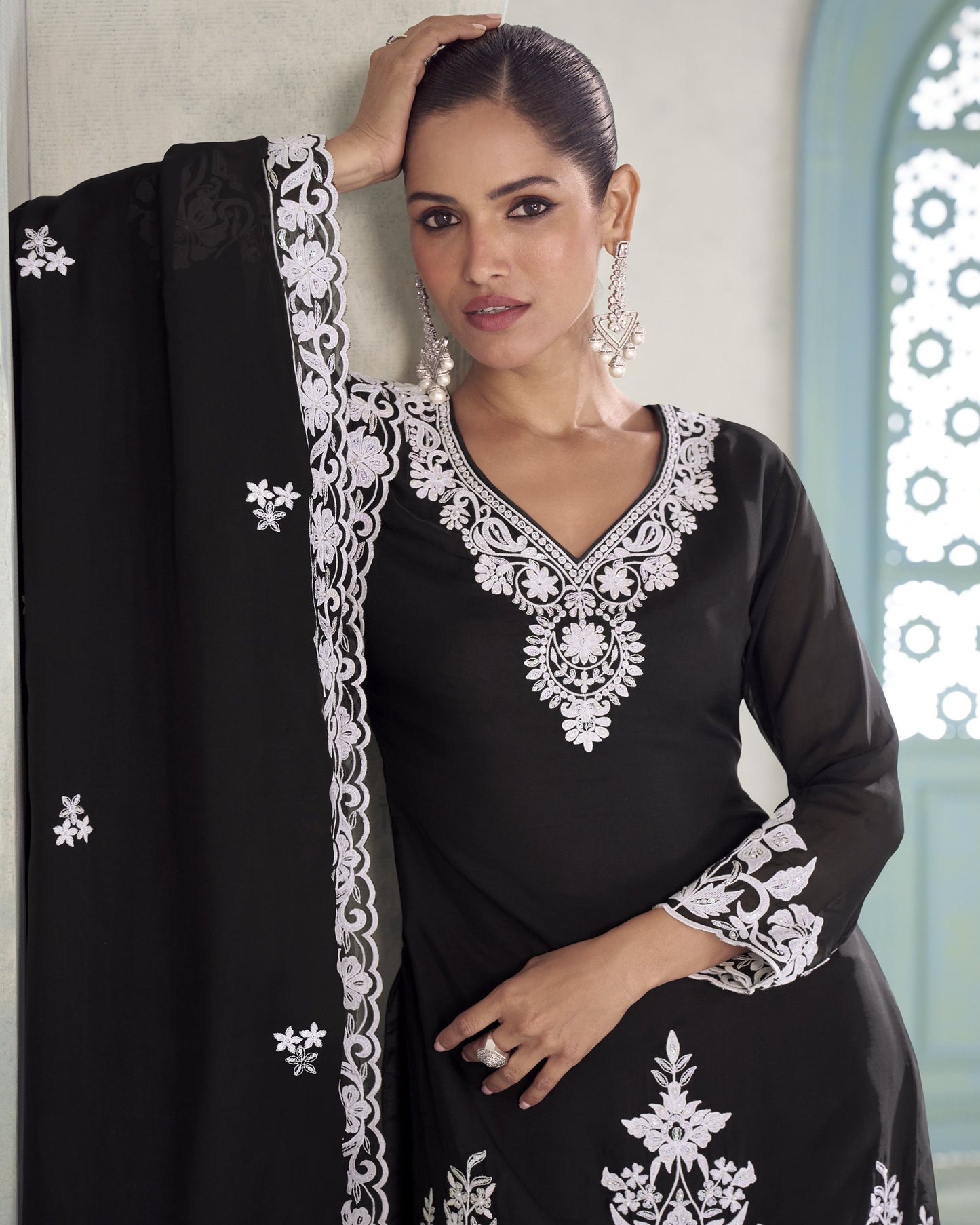 Woman wearing a black dress with white embroidery in a decorative setting