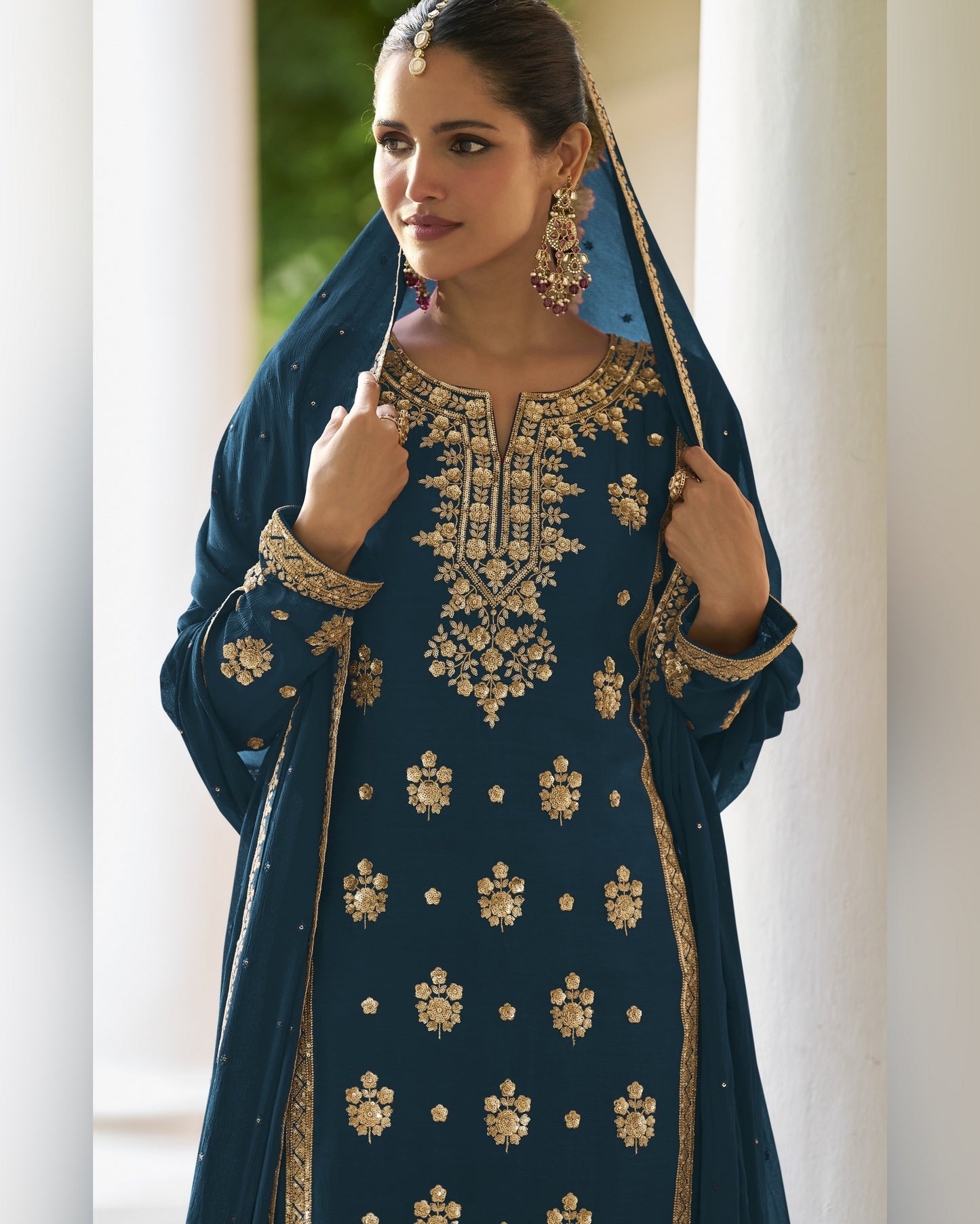 Woman wearing a blue embroidered traditional outfit with gold details.