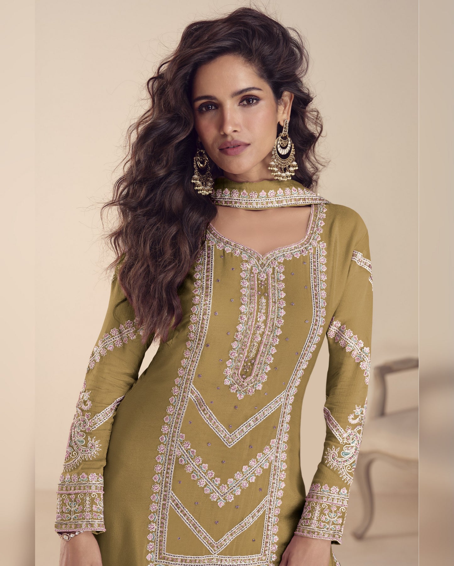 Woman wearing a green embroidered traditional outfit with a beige background