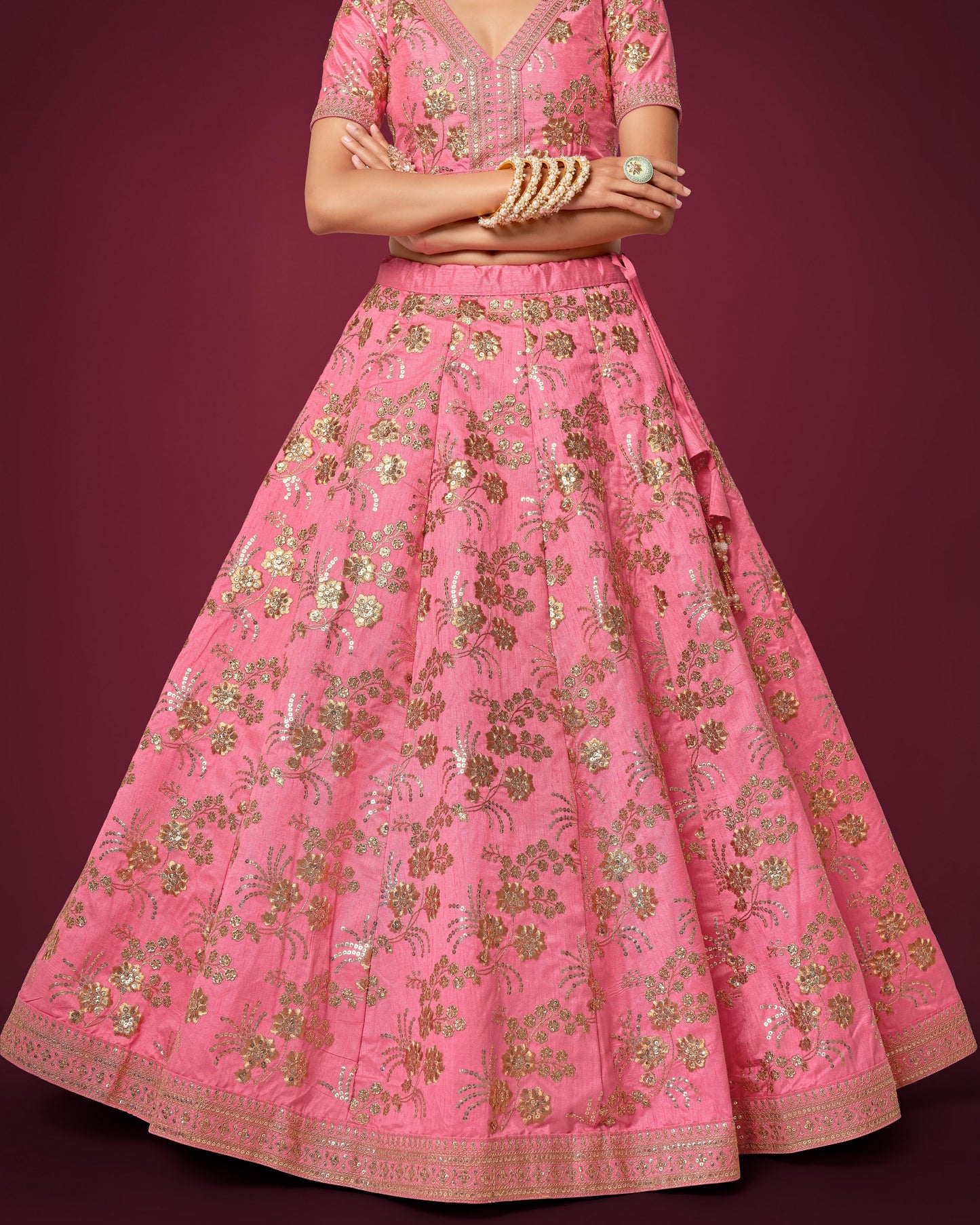 Pink embroidered traditional outfit with gold details on a dark red background