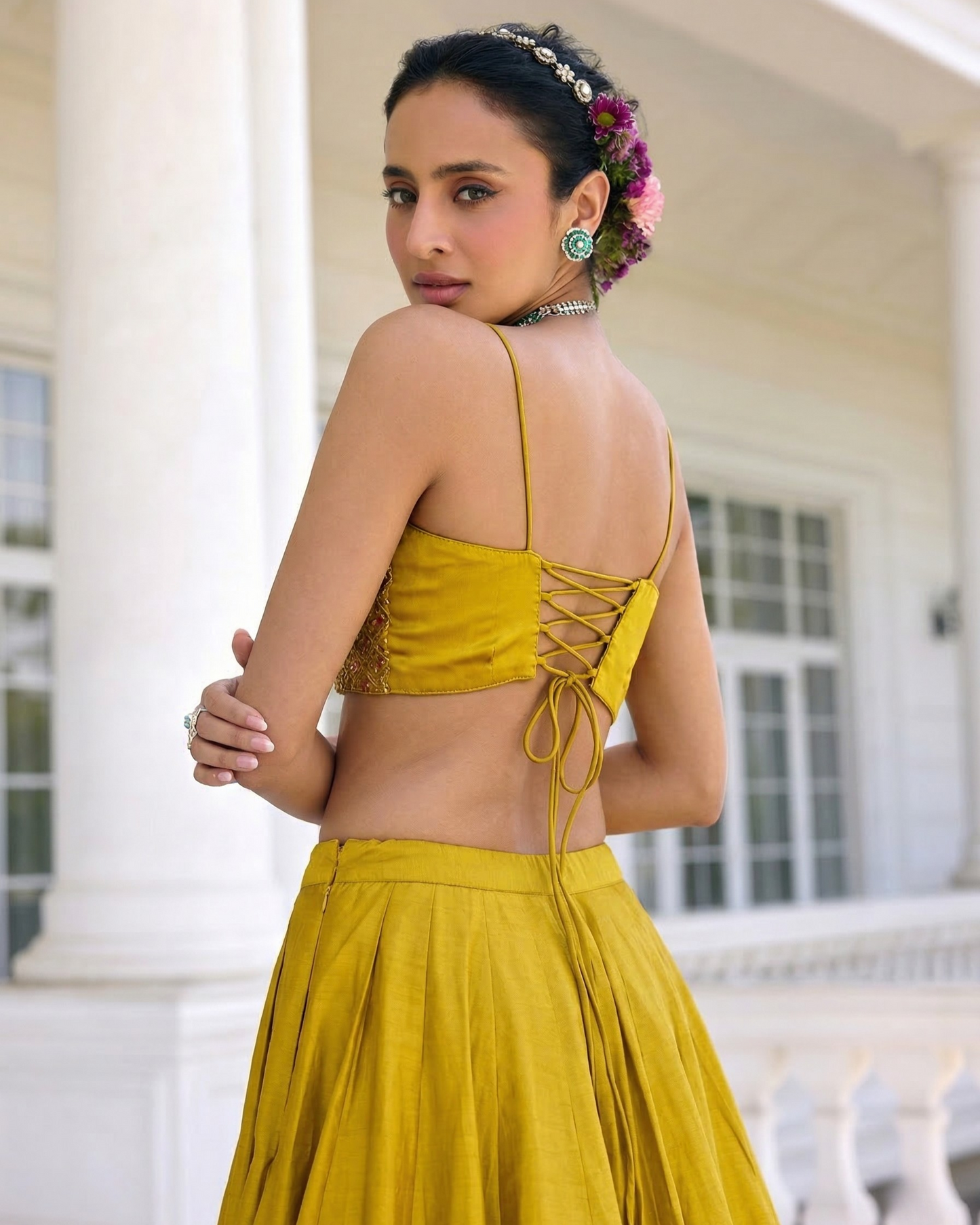 Woman wearing a yellow traditional outfit with a white building in the background