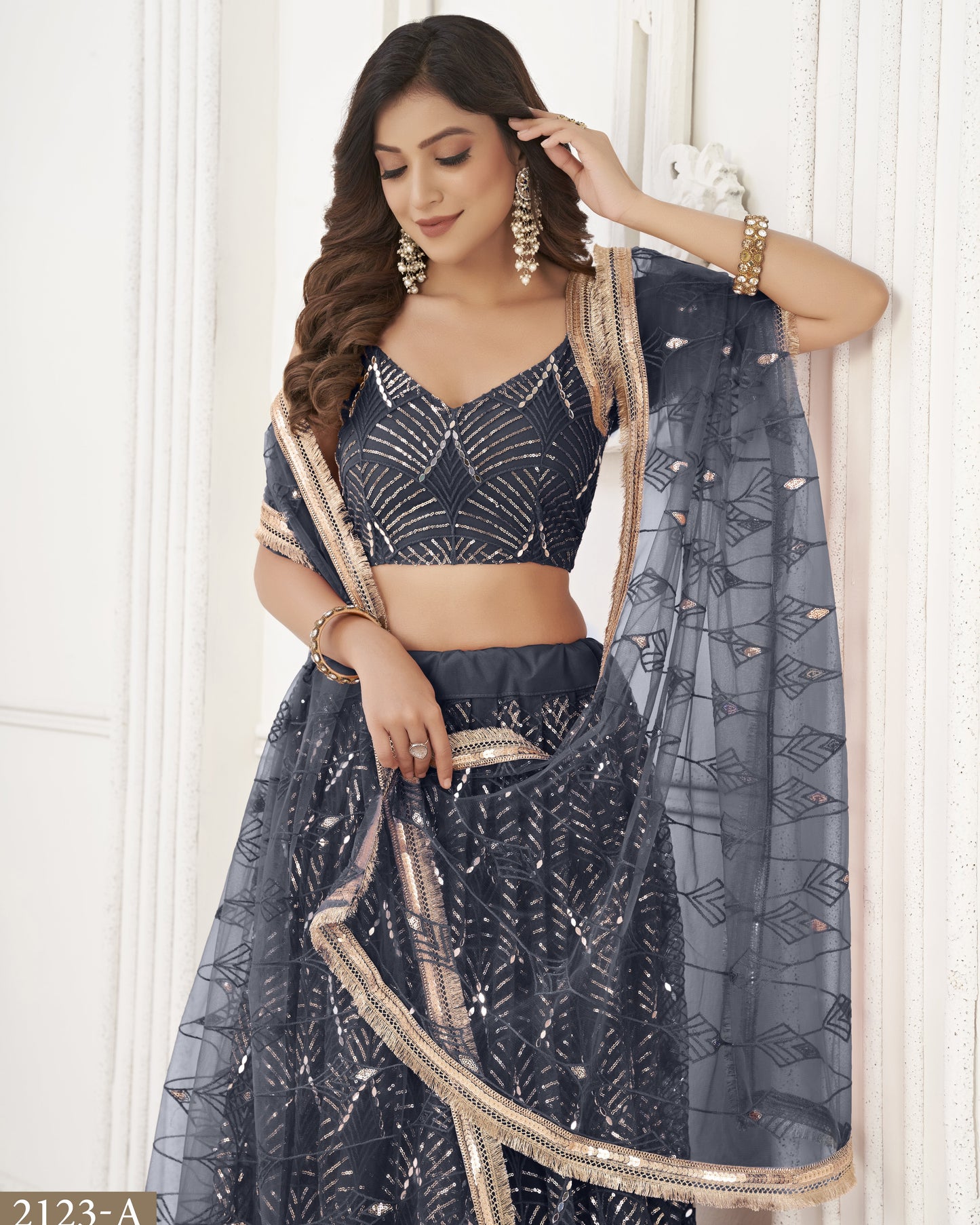 Woman wearing a dark blue traditional outfit with gold accents against a white background