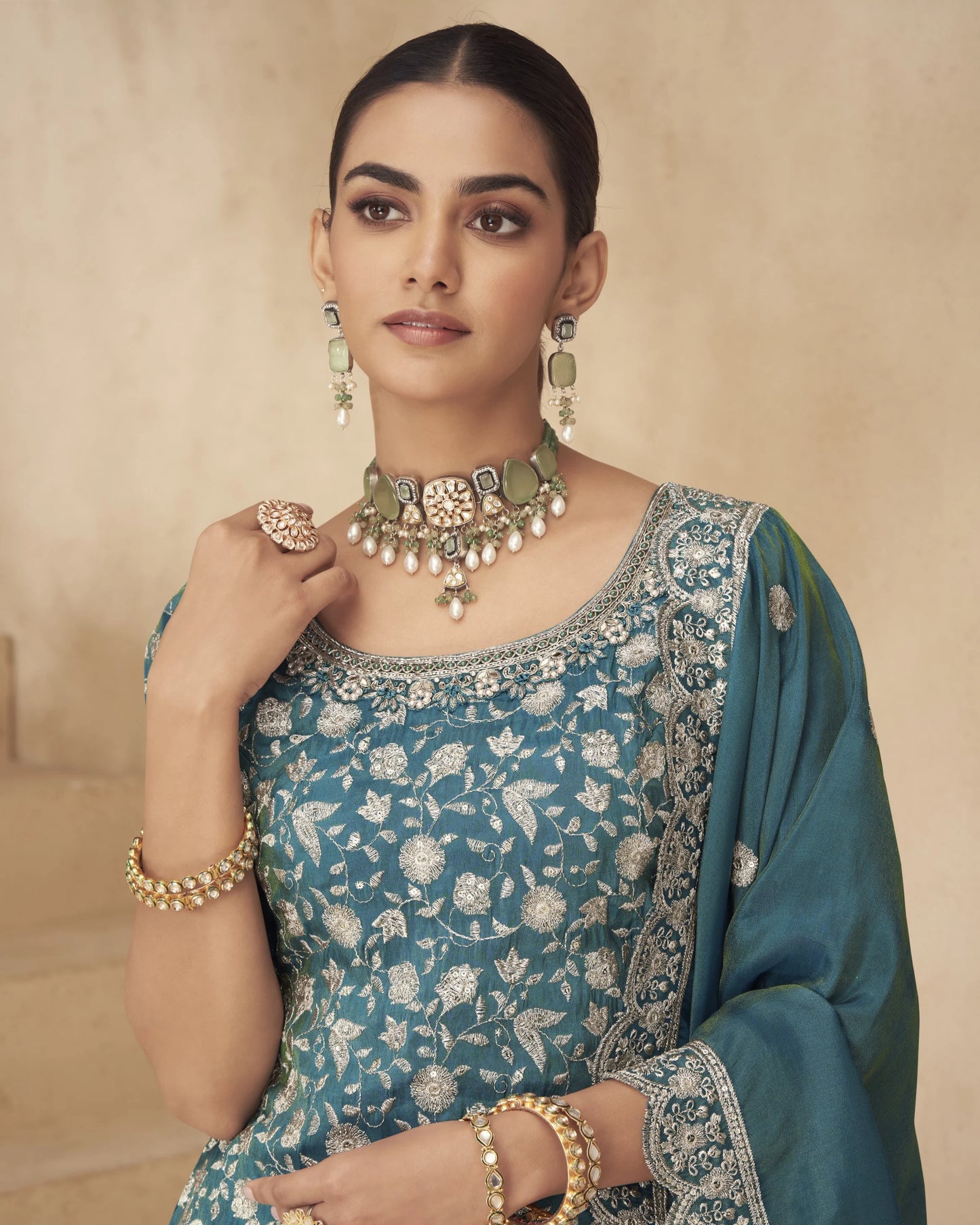 Woman in traditional attire with jewelry against a beige background