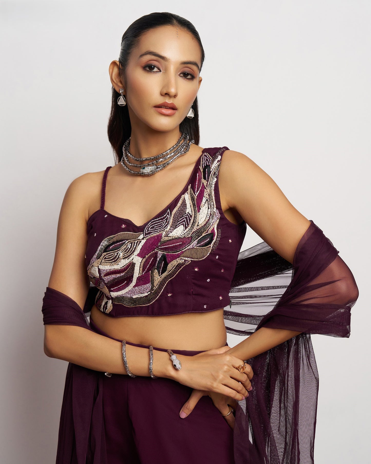 Woman wearing a purple traditional outfit with intricate designs on a plain background