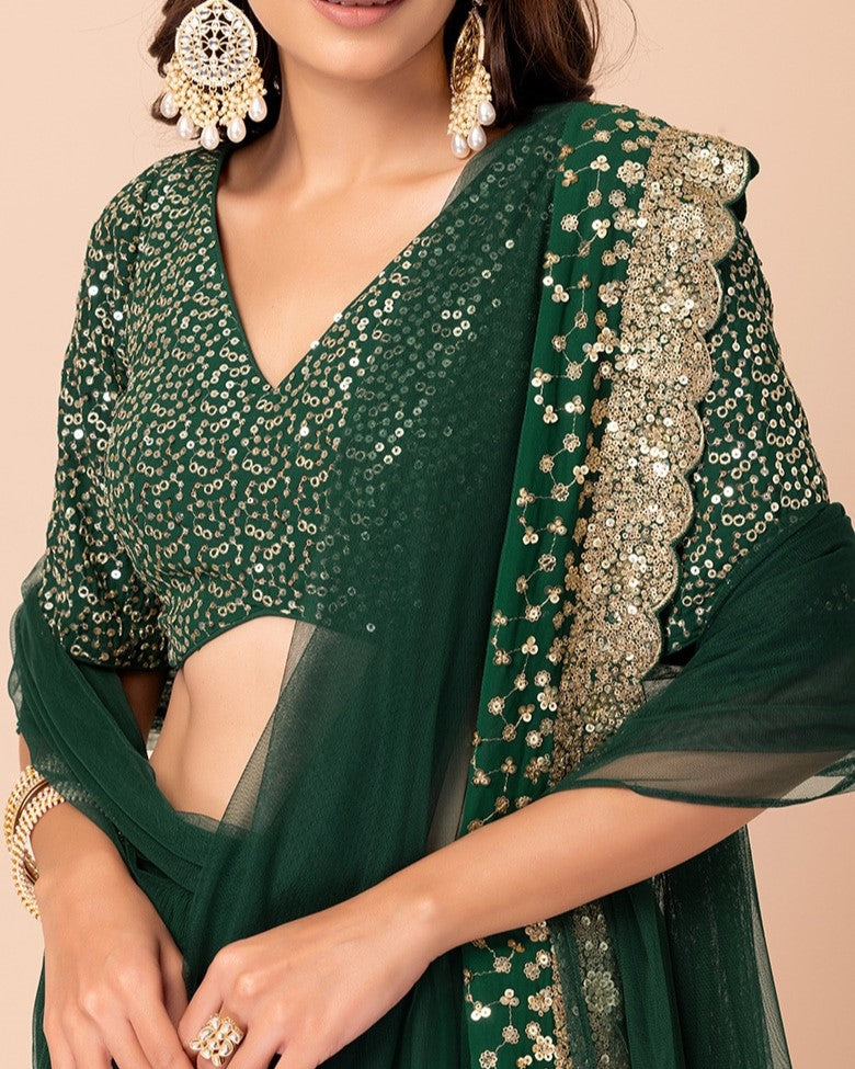 Green saree with gold embroidery on a beige background