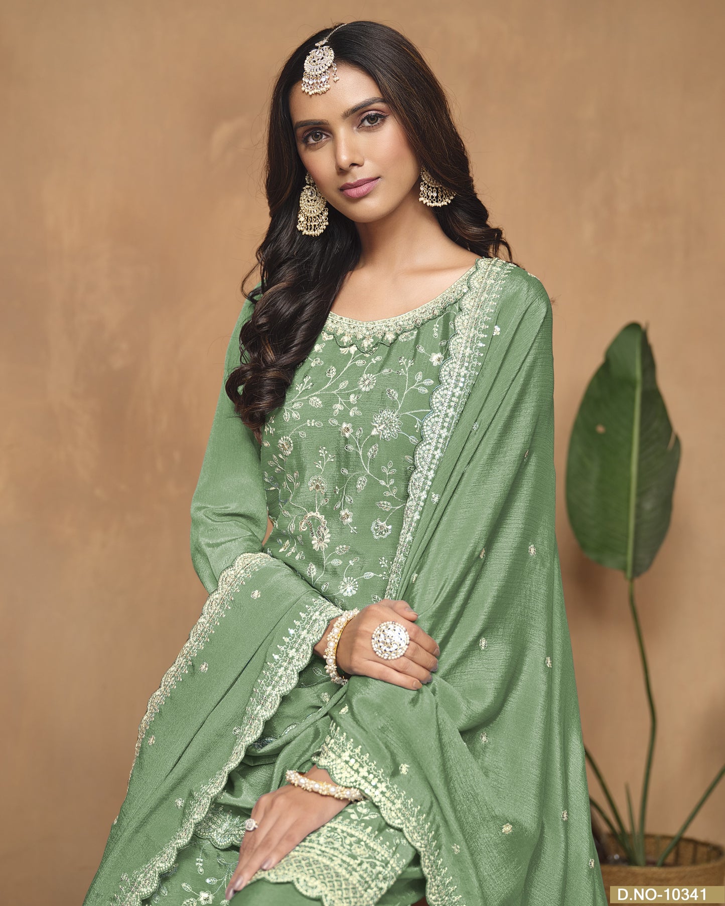 Woman wearing a green traditional outfit with embroidery against a beige background