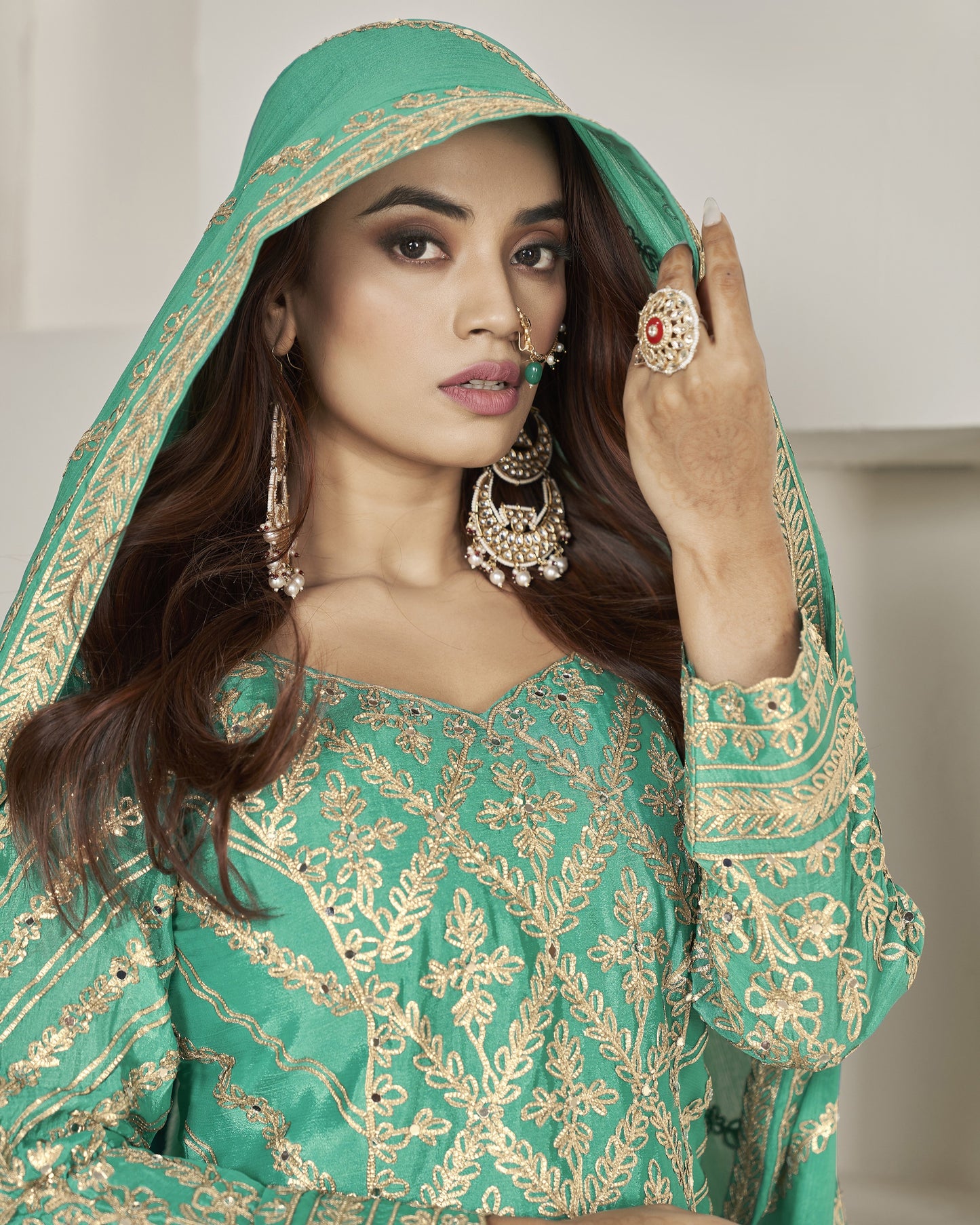 Woman wearing a green embroidered traditional outfit with gold details.