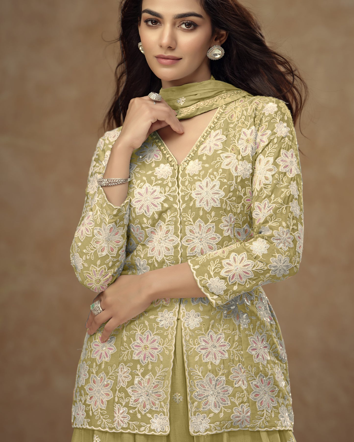 Woman wearing a green floral embroidered outfit against a brown background