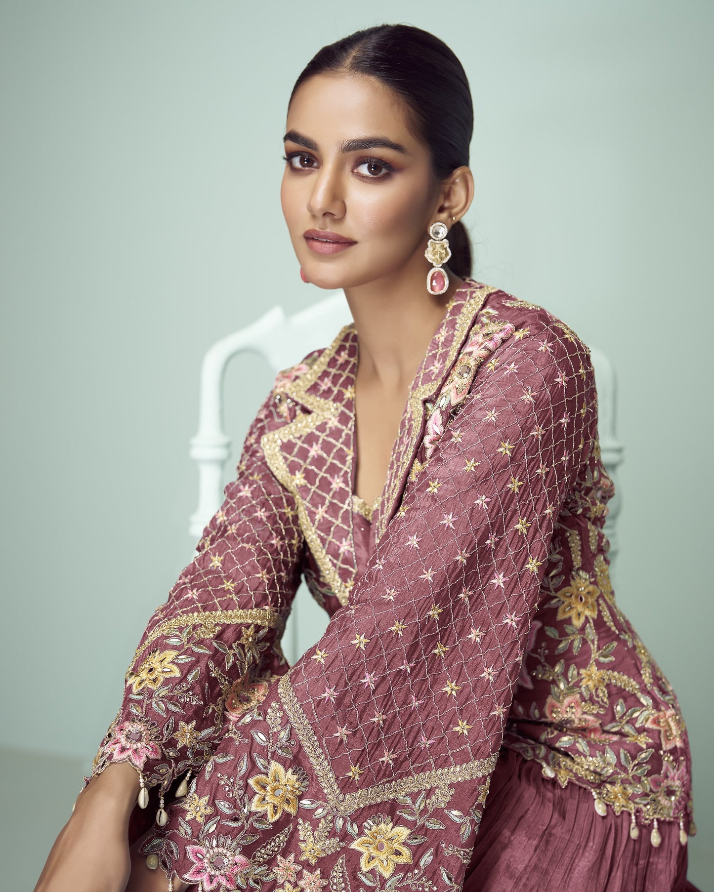 Woman wearing a traditional embroidered outfit with a neutral background