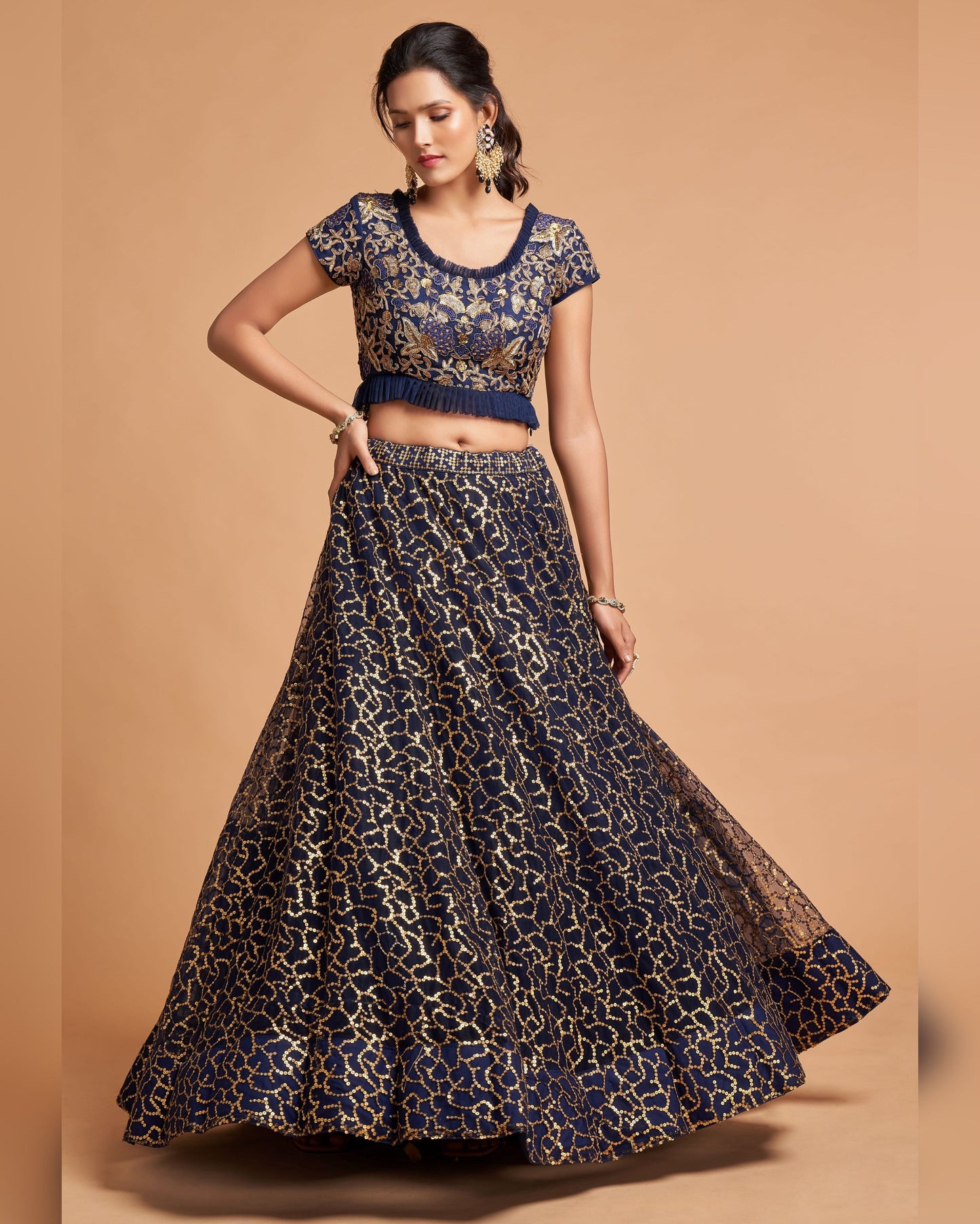 Woman wearing a navy blue and gold patterned outfit on a beige background