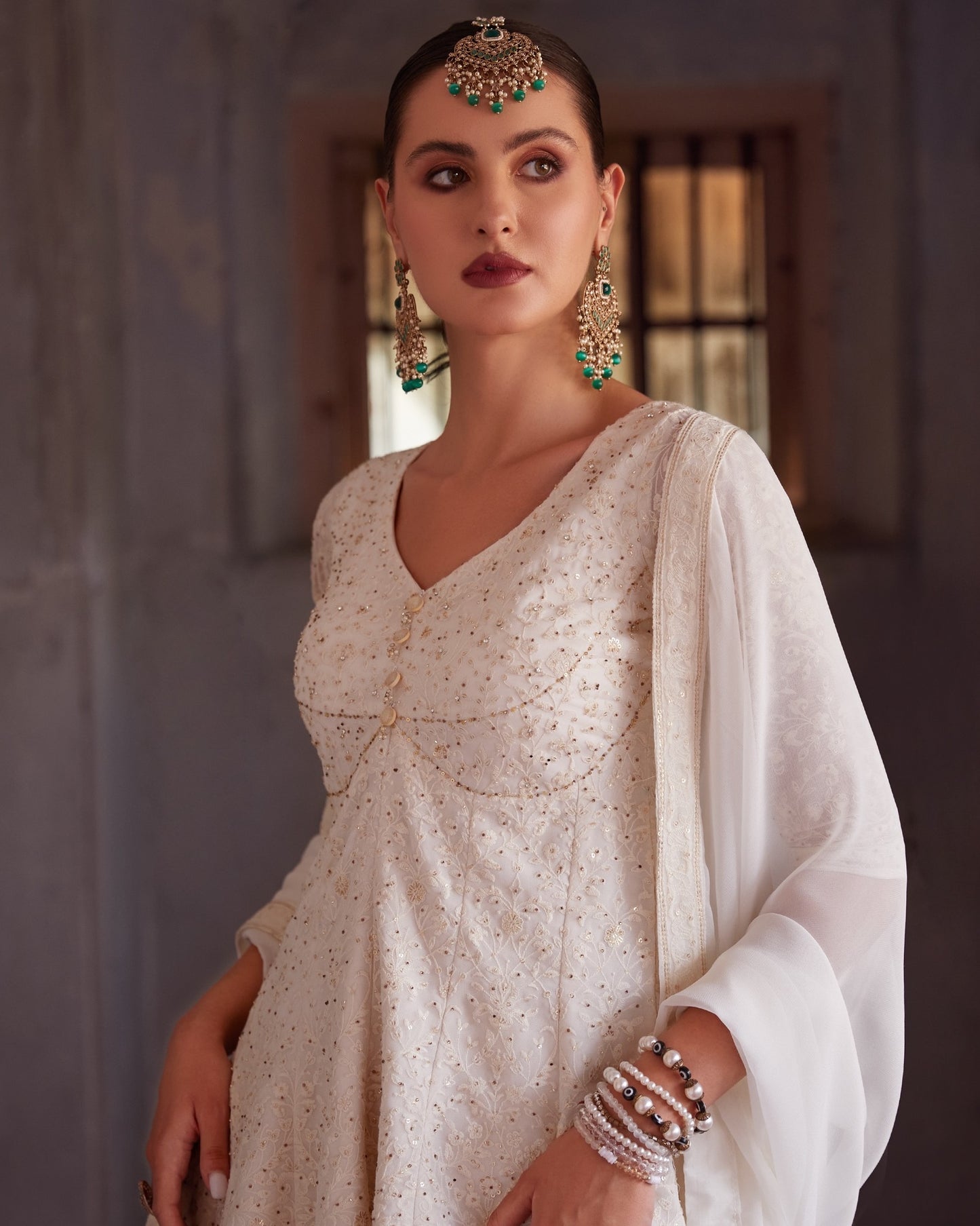 Woman wearing a traditional outfit with jewelry against a neutral background
