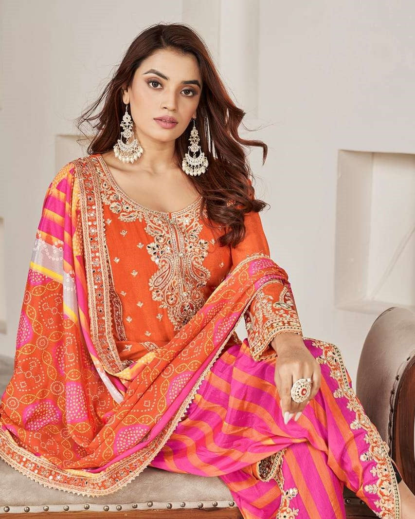 Woman wearing a traditional orange and pink embroidered outfit with jewelry.