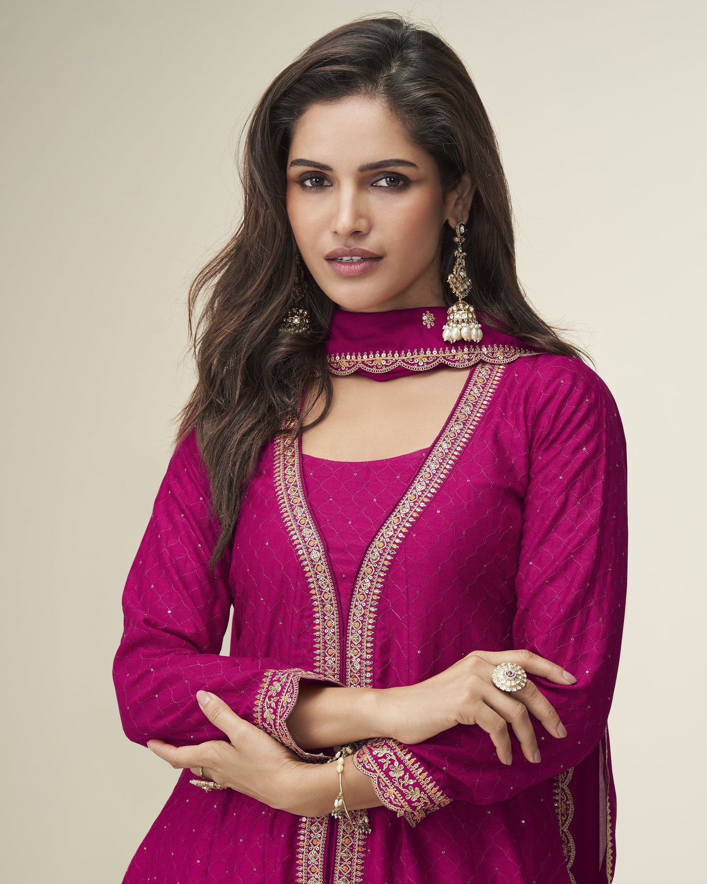 Woman wearing a pink traditional outfit with gold embroidery on a beige background