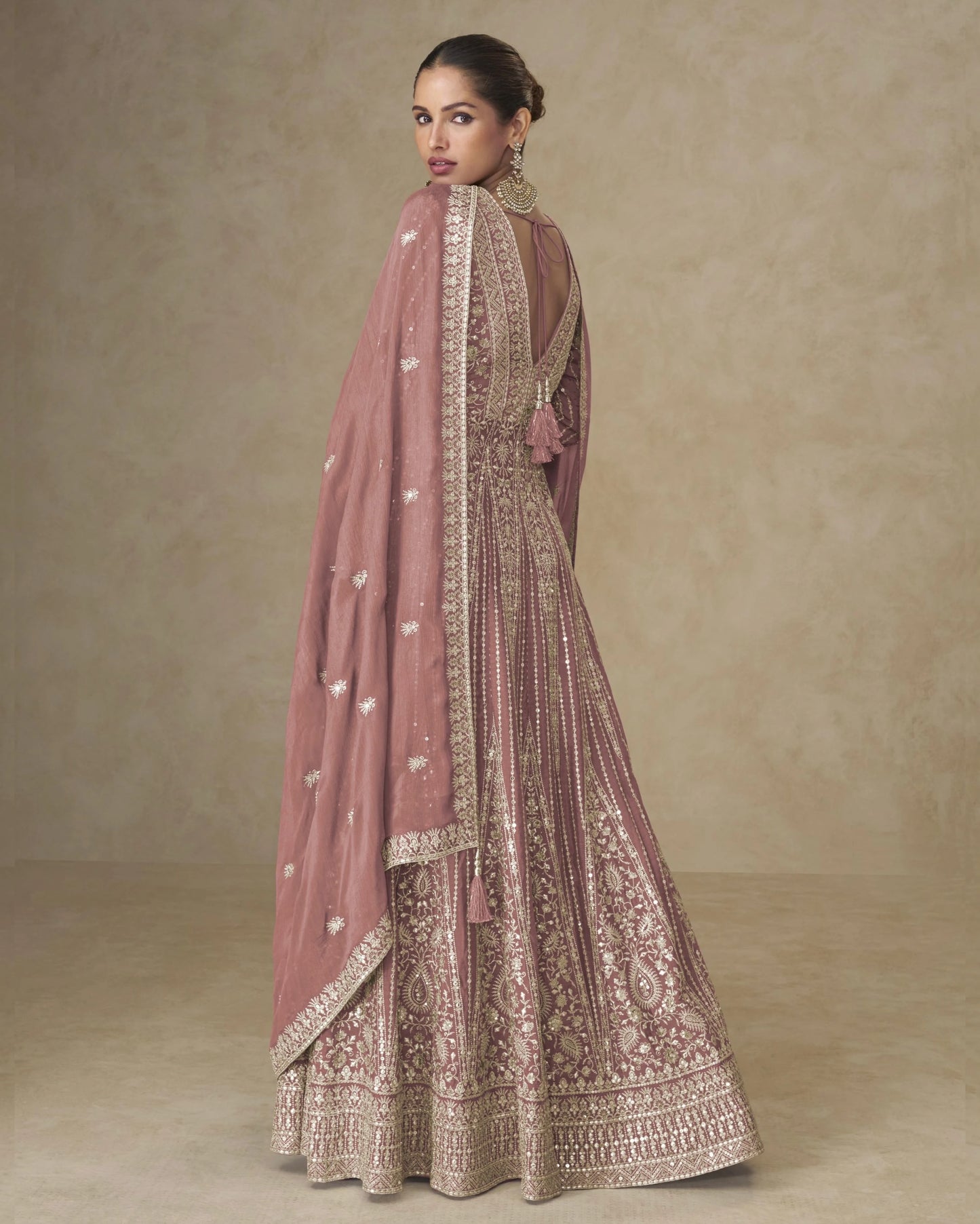Woman wearing a traditional outfit with intricate patterns on a beige background