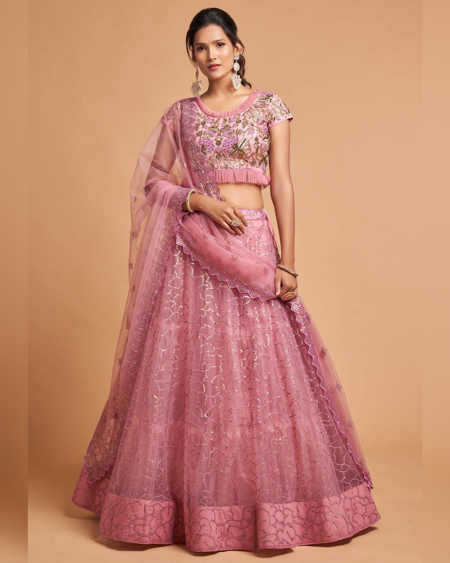 Woman wearing a pink embroidered traditional outfit on a beige background