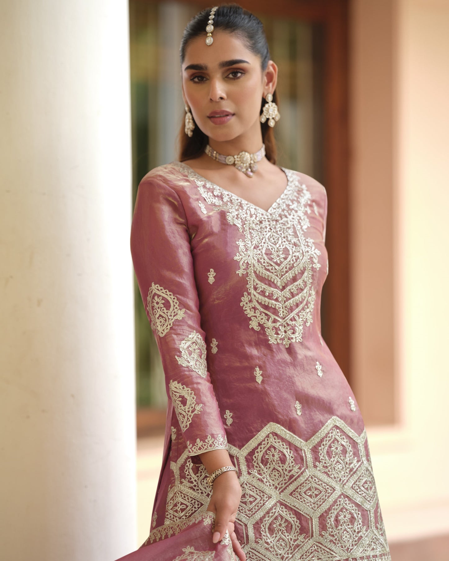 Woman wearing a pink traditional outfit with white embroidery in an outdoor setting