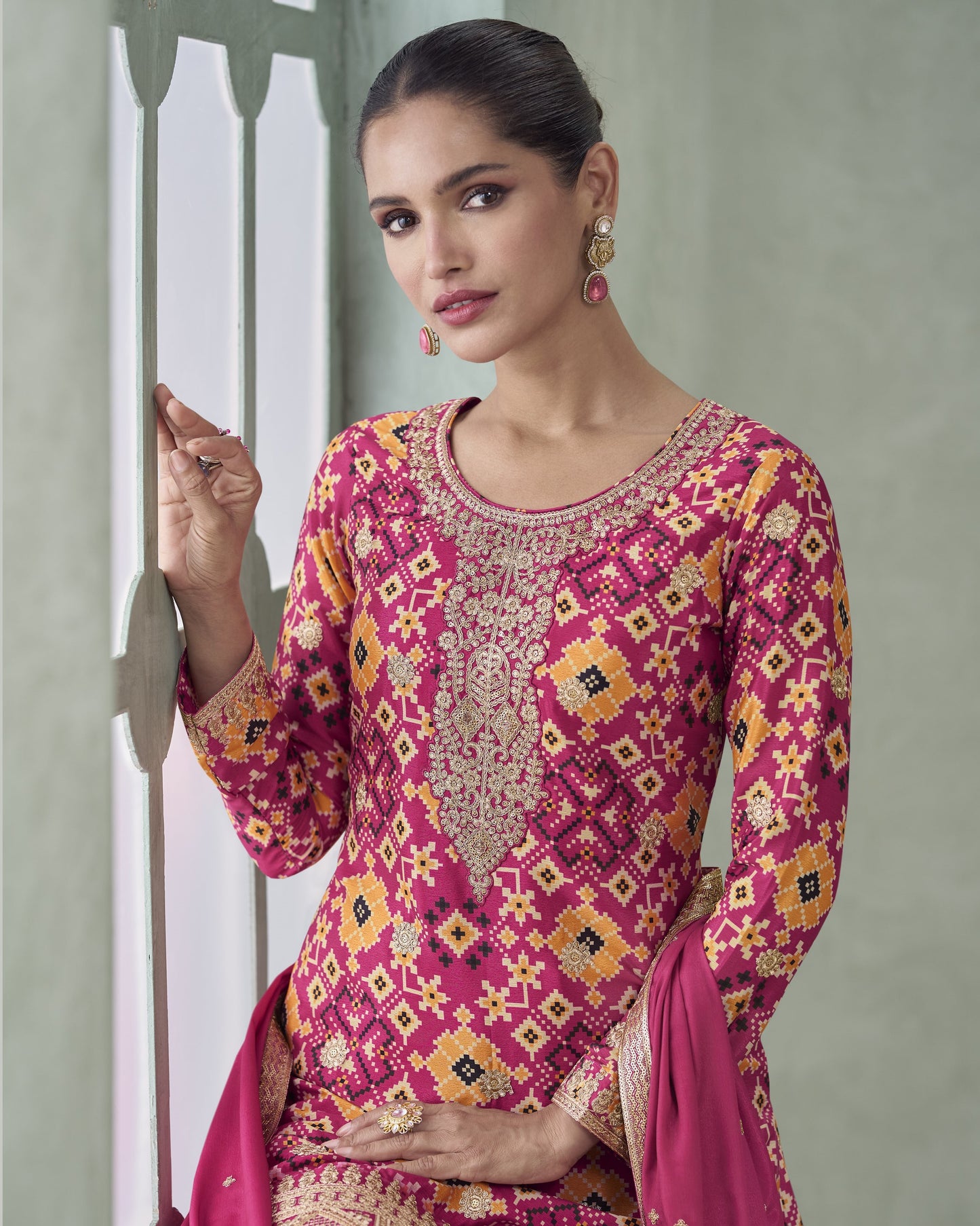 Woman wearing a pink and gold embroidered traditional outfit against a neutral background