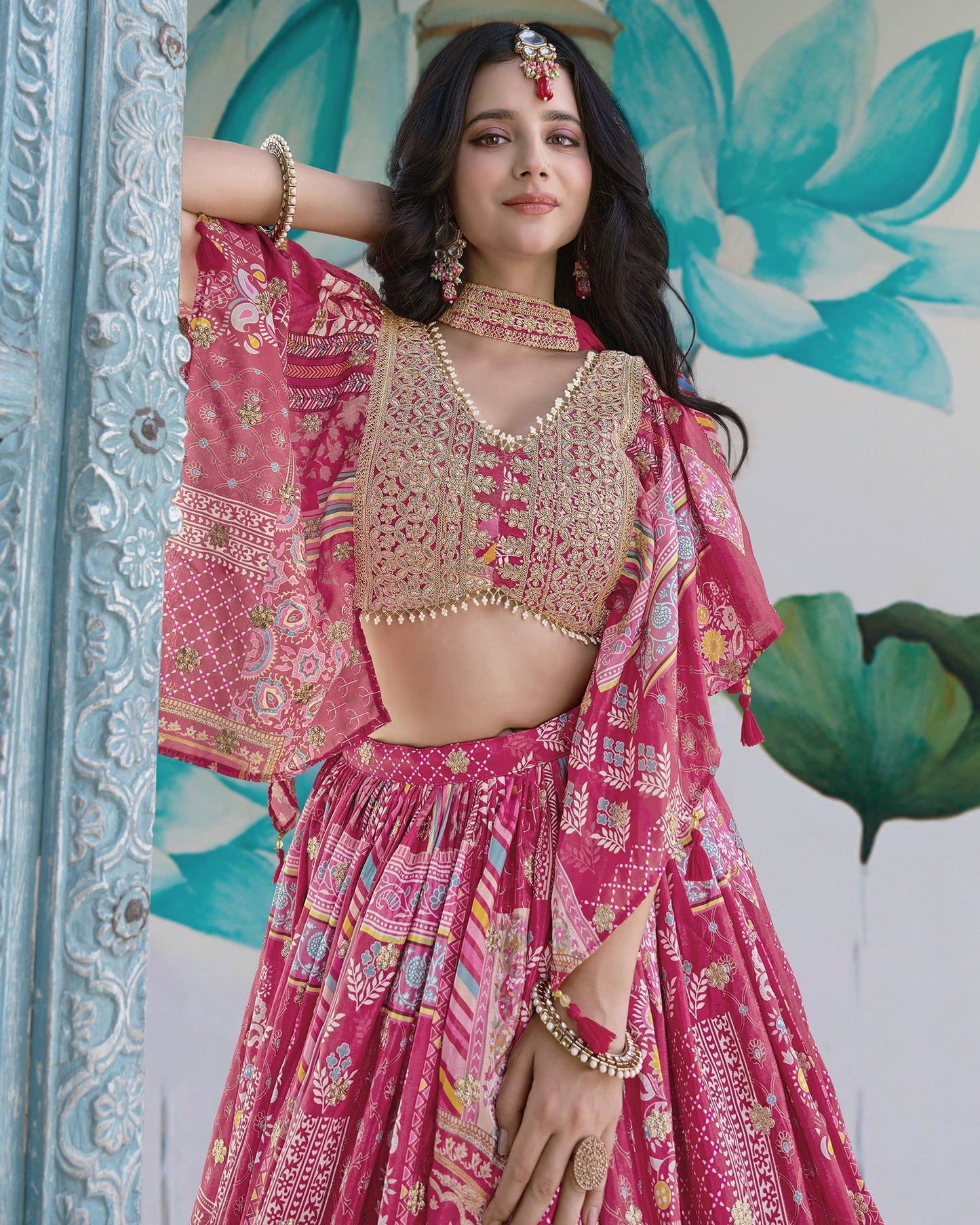 Woman in a pink traditional outfit with gold details against a decorative background