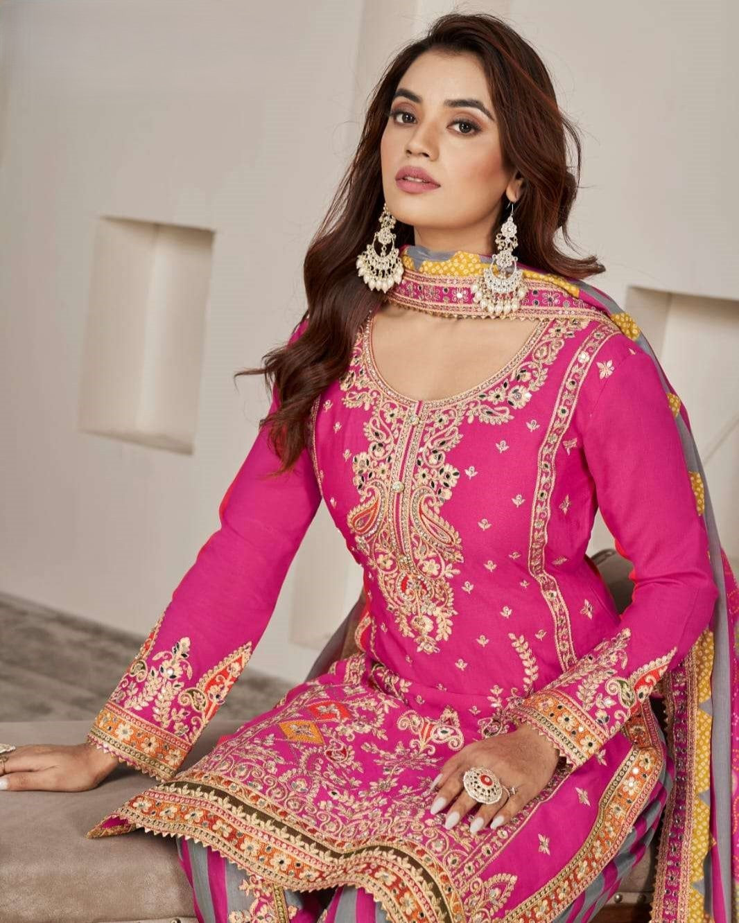Woman wearing a pink embroidered traditional outfit with gold details.