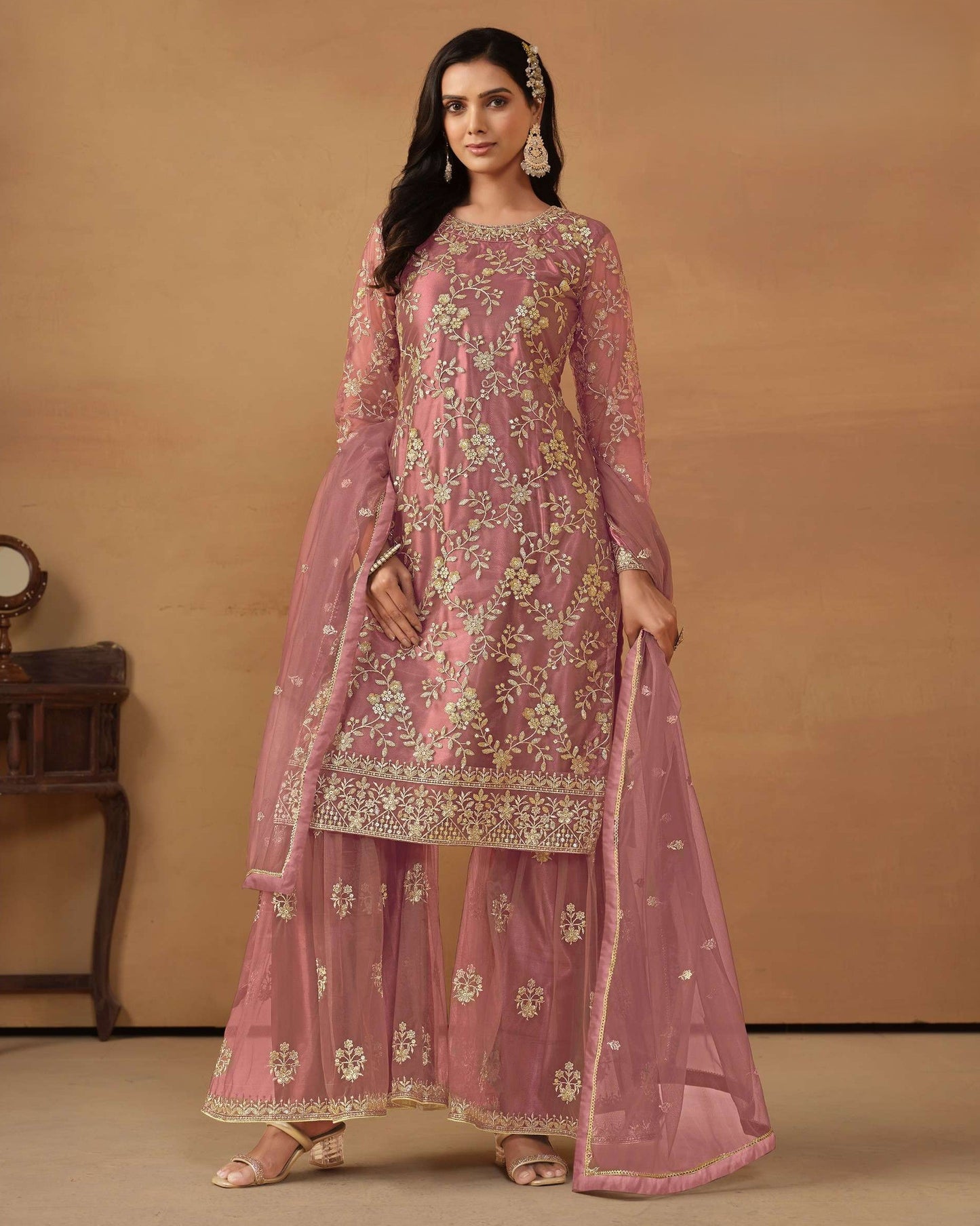 Woman wearing a pink embroidered traditional outfit on a beige background