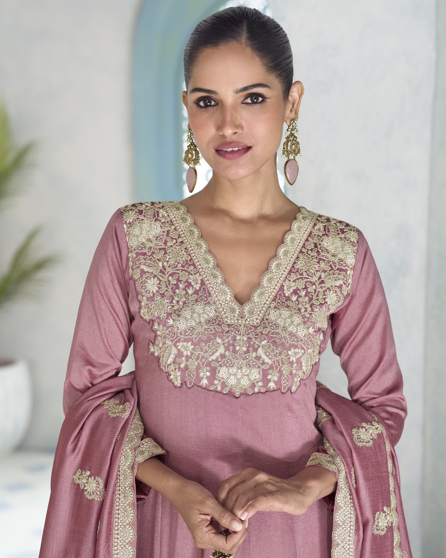 Woman wearing a pink traditional outfit with intricate lace details.