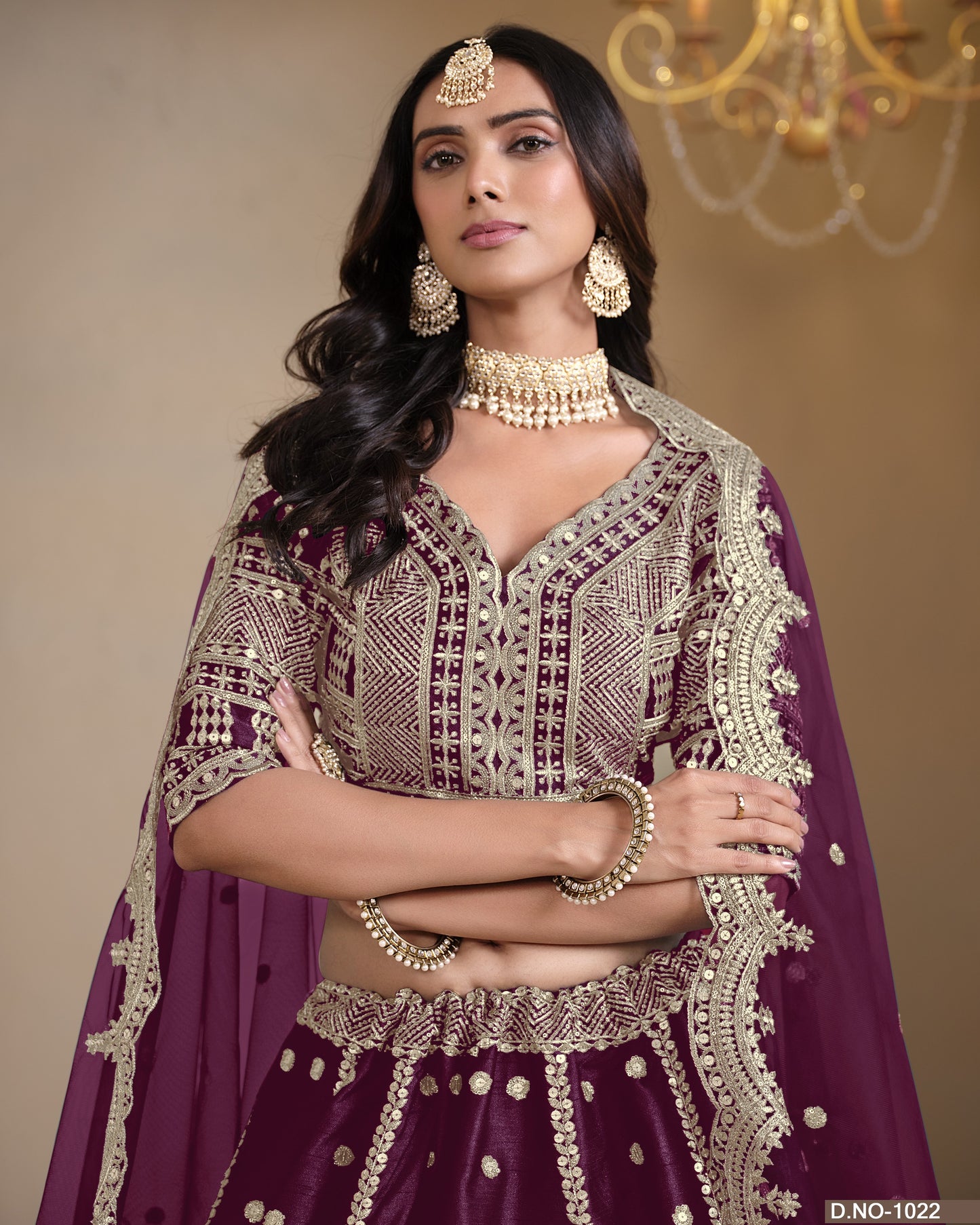 Woman in traditional maroon and gold embroidered outfit with jewelry against a neutral background